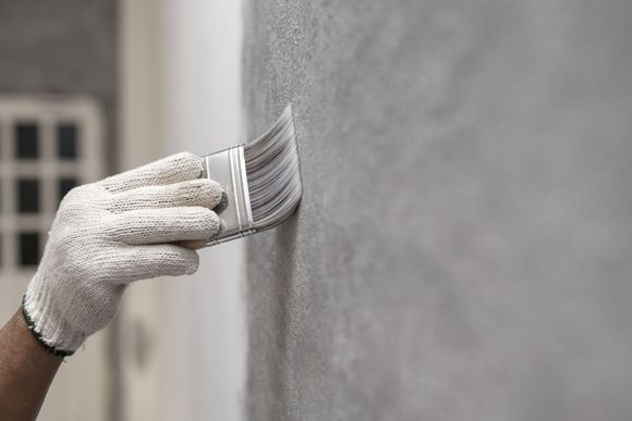 A person is painting a wall with a brush.