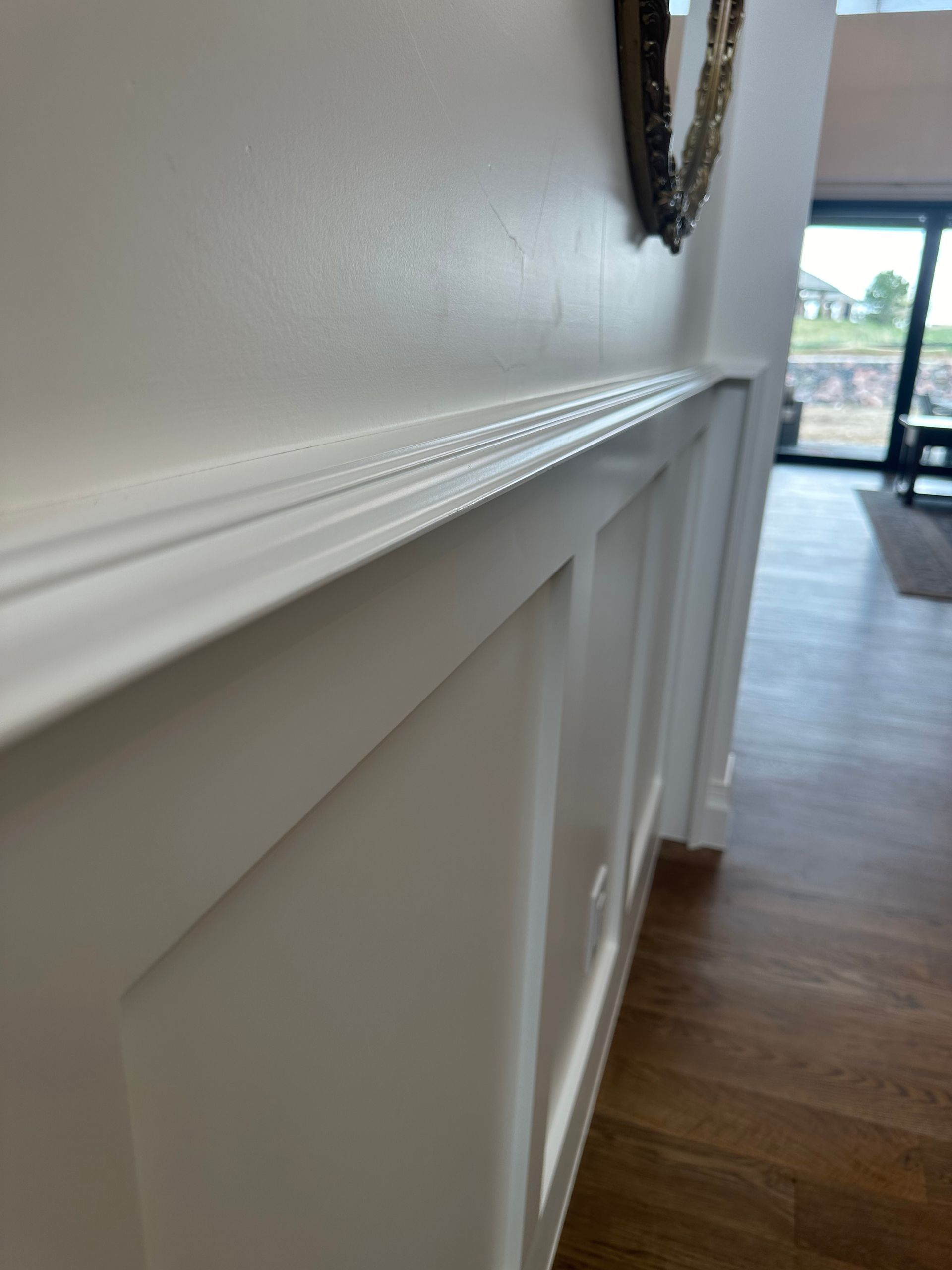 A white wall with a mirror on it in a hallway.