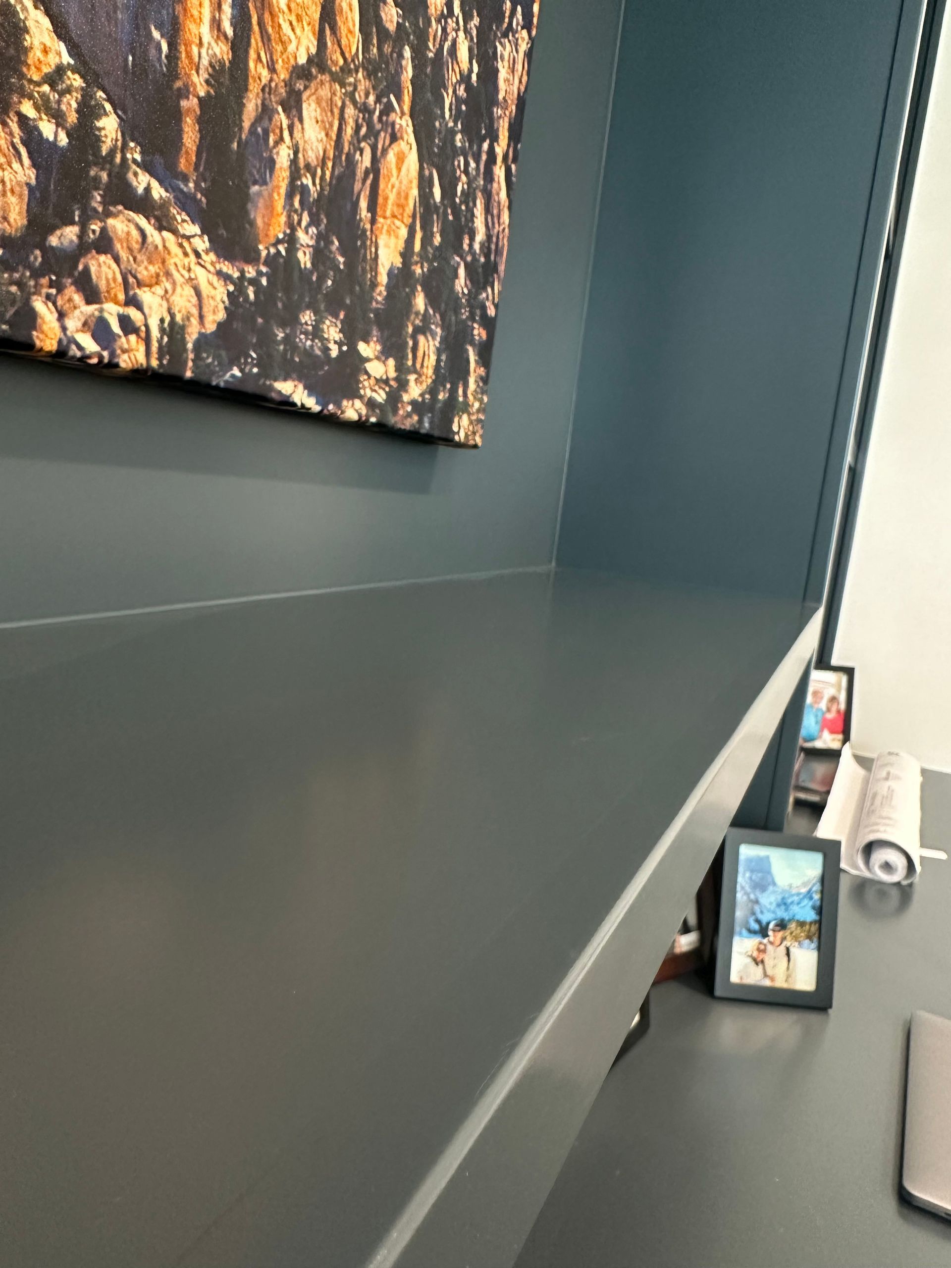 A desk with a picture on it and a picture on the wall above it.