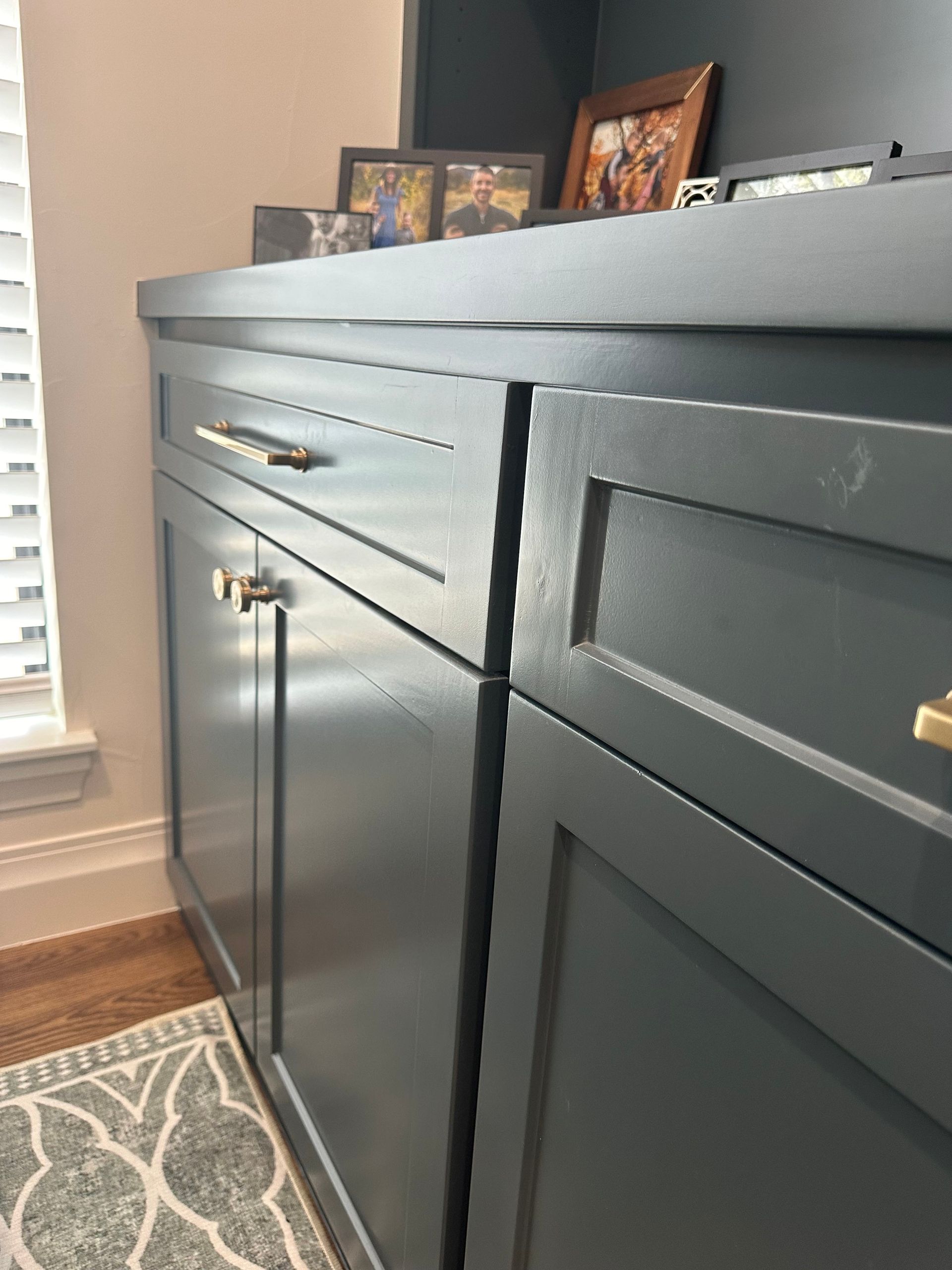 A close up of a cabinet with pictures on top of it in a living room.