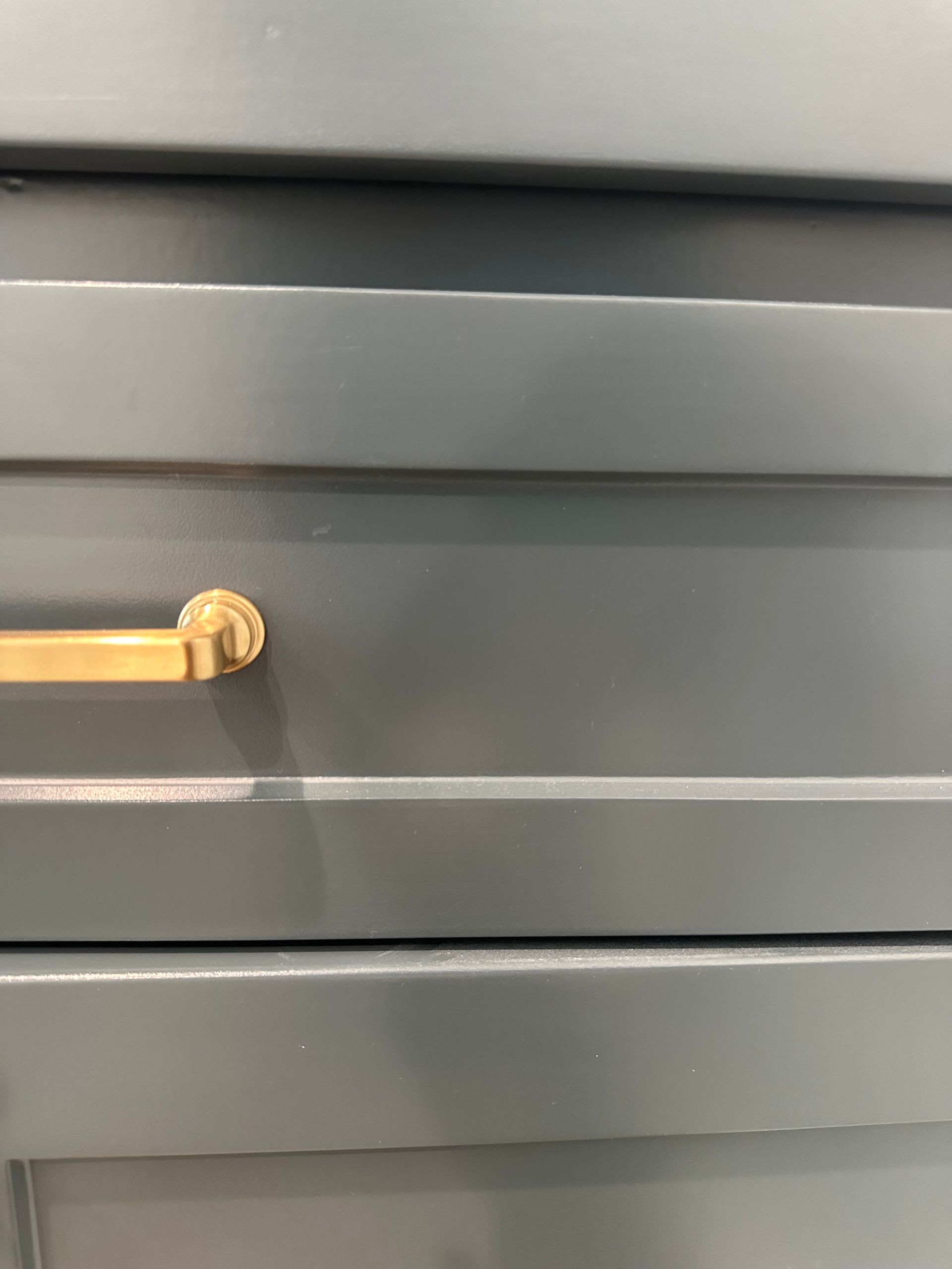 A close up of a gray cabinet with a gold handle.