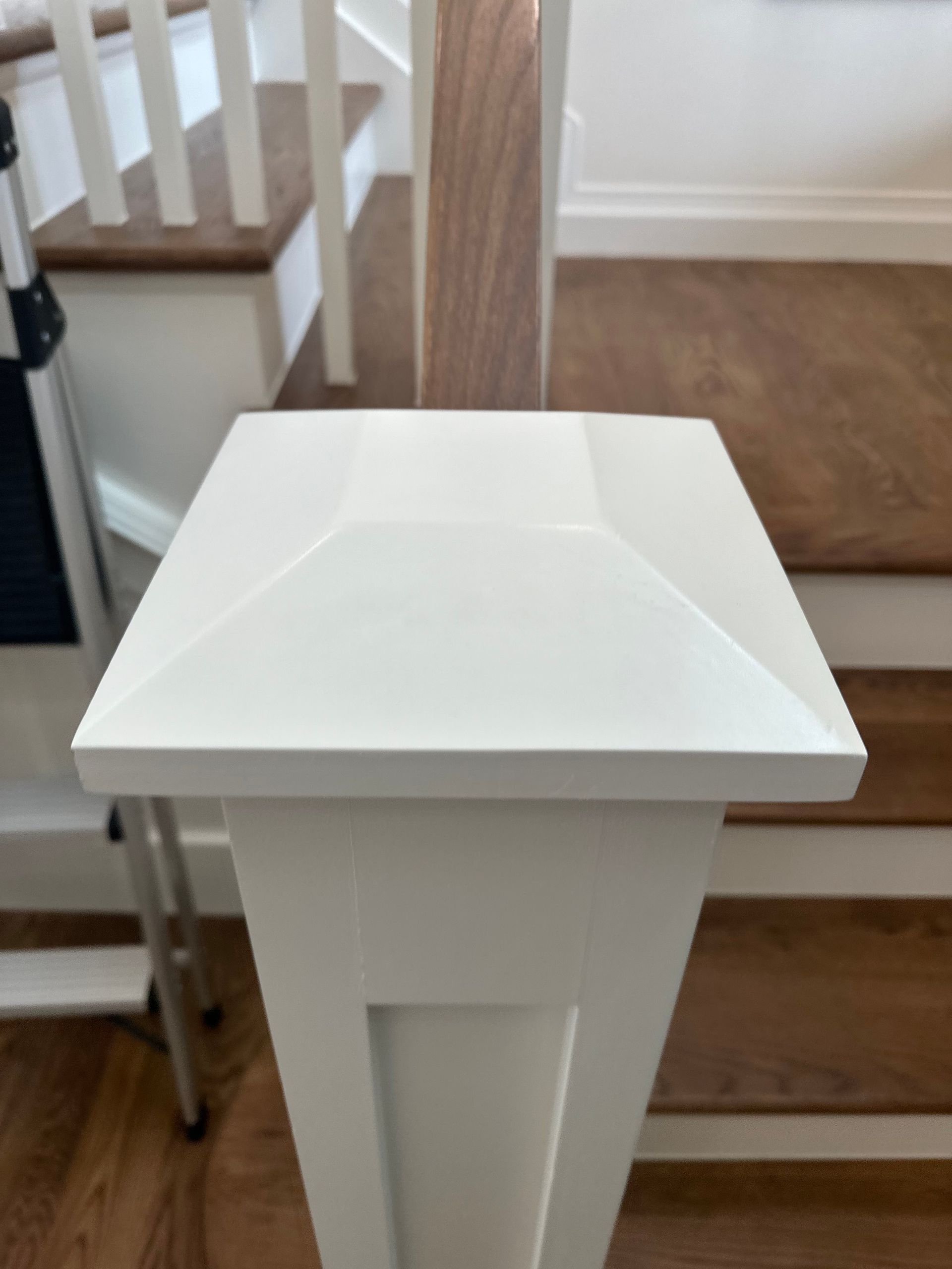 A white pedestal is sitting in front of a set of stairs.