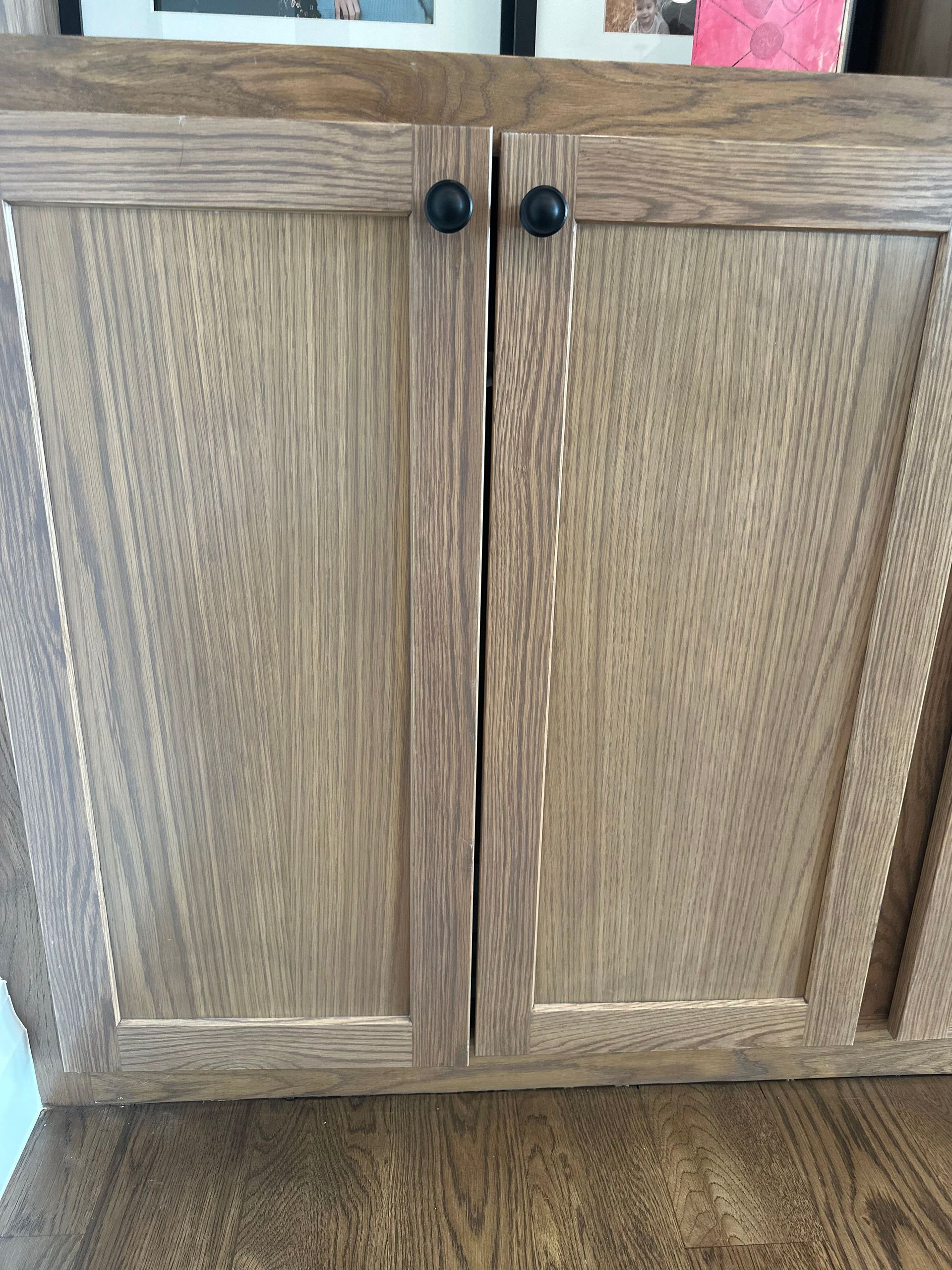 A wooden cabinet with two doors is sitting on a wooden floor.