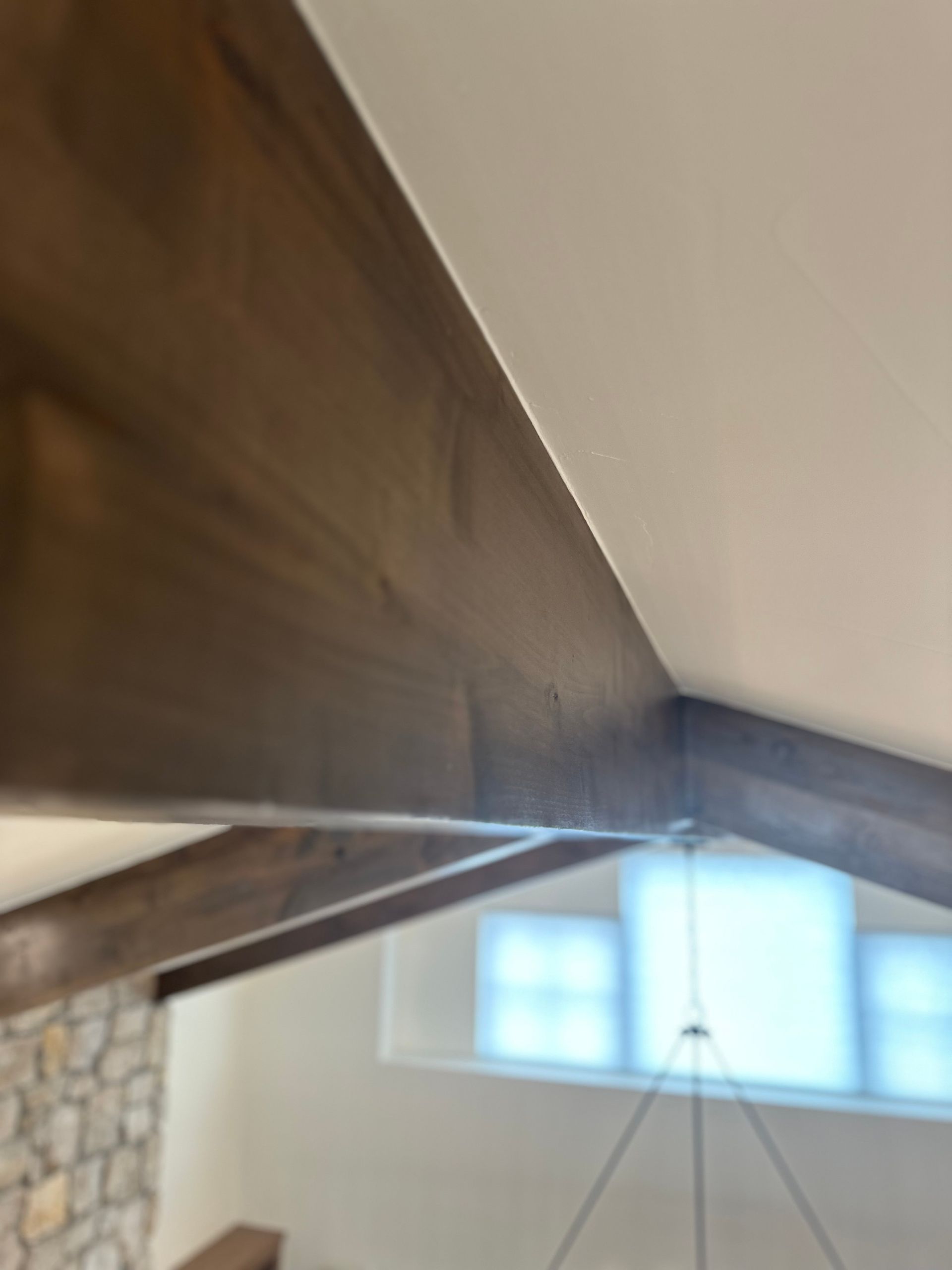 A ceiling with wooden beams and a chandelier hanging from it