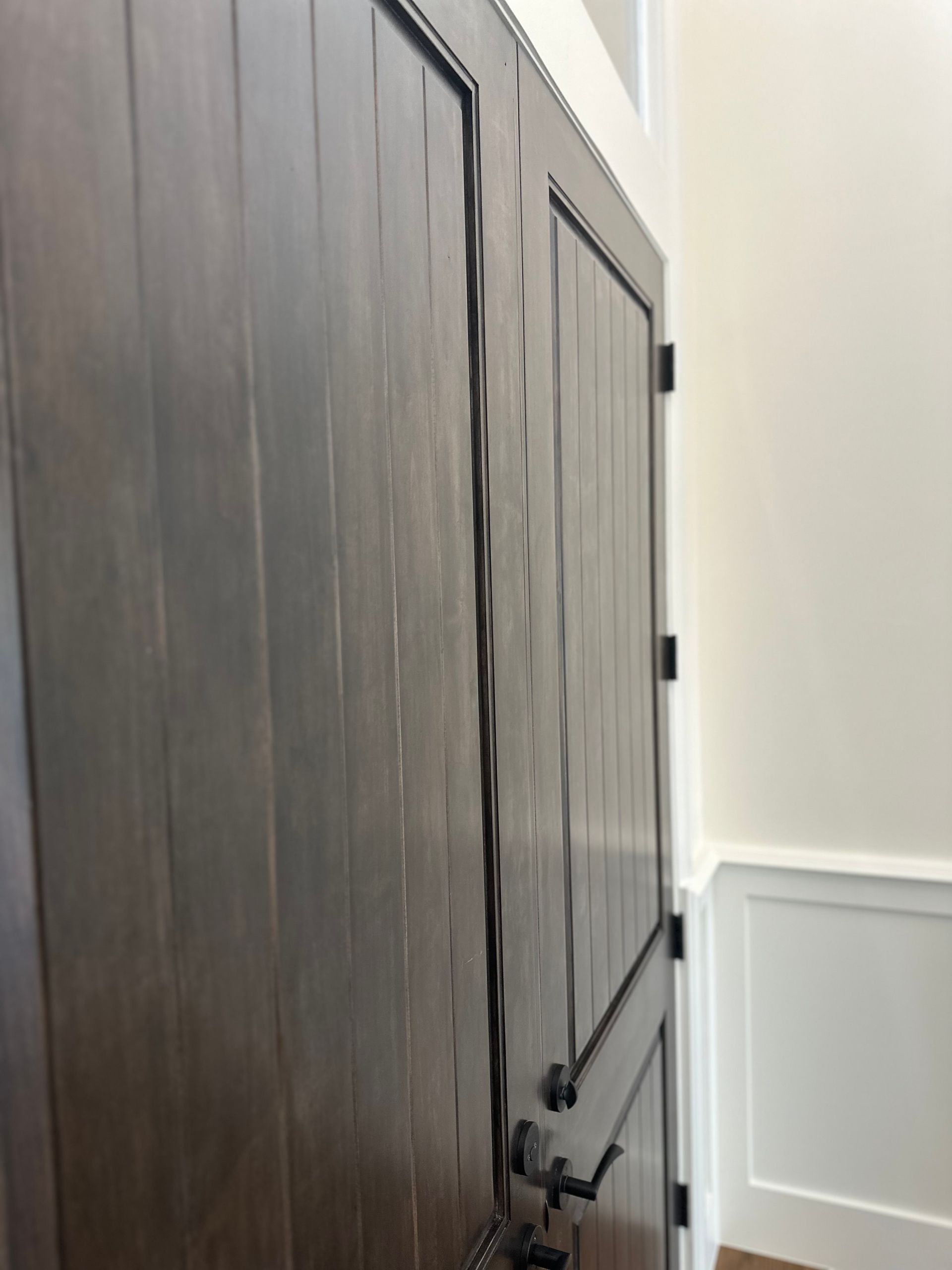 A close up of a wooden door with a black handle