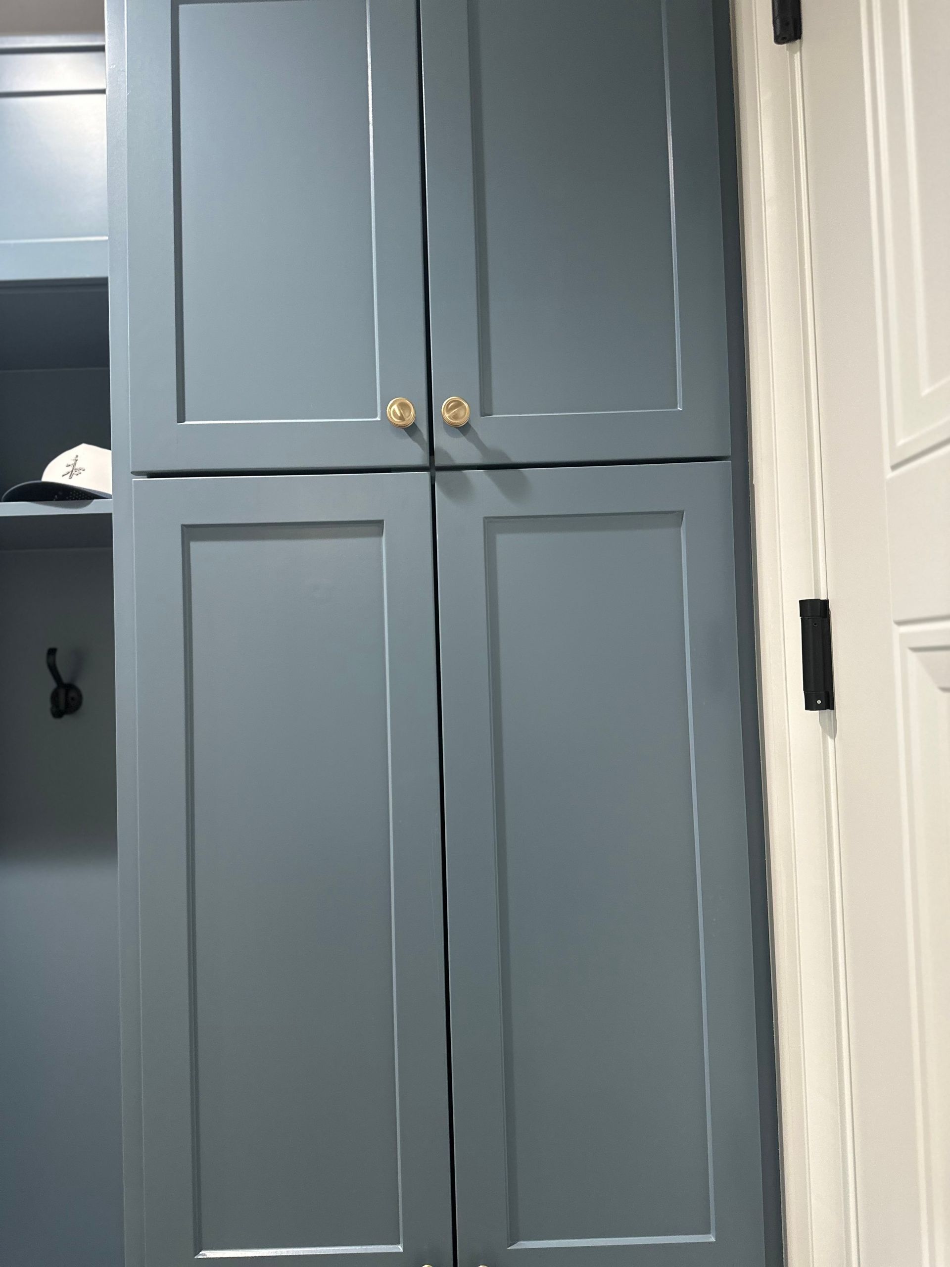 A gray cabinet with gold handles is next to a white door