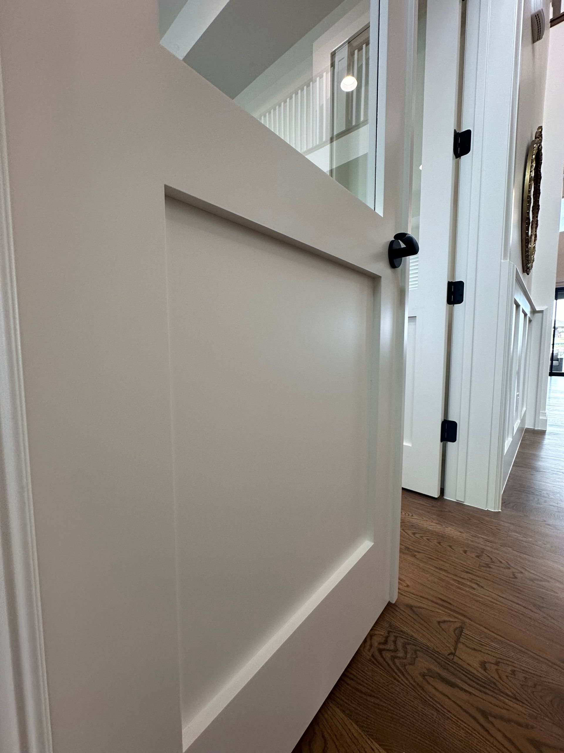 A white door in a hallway with a wooden floor