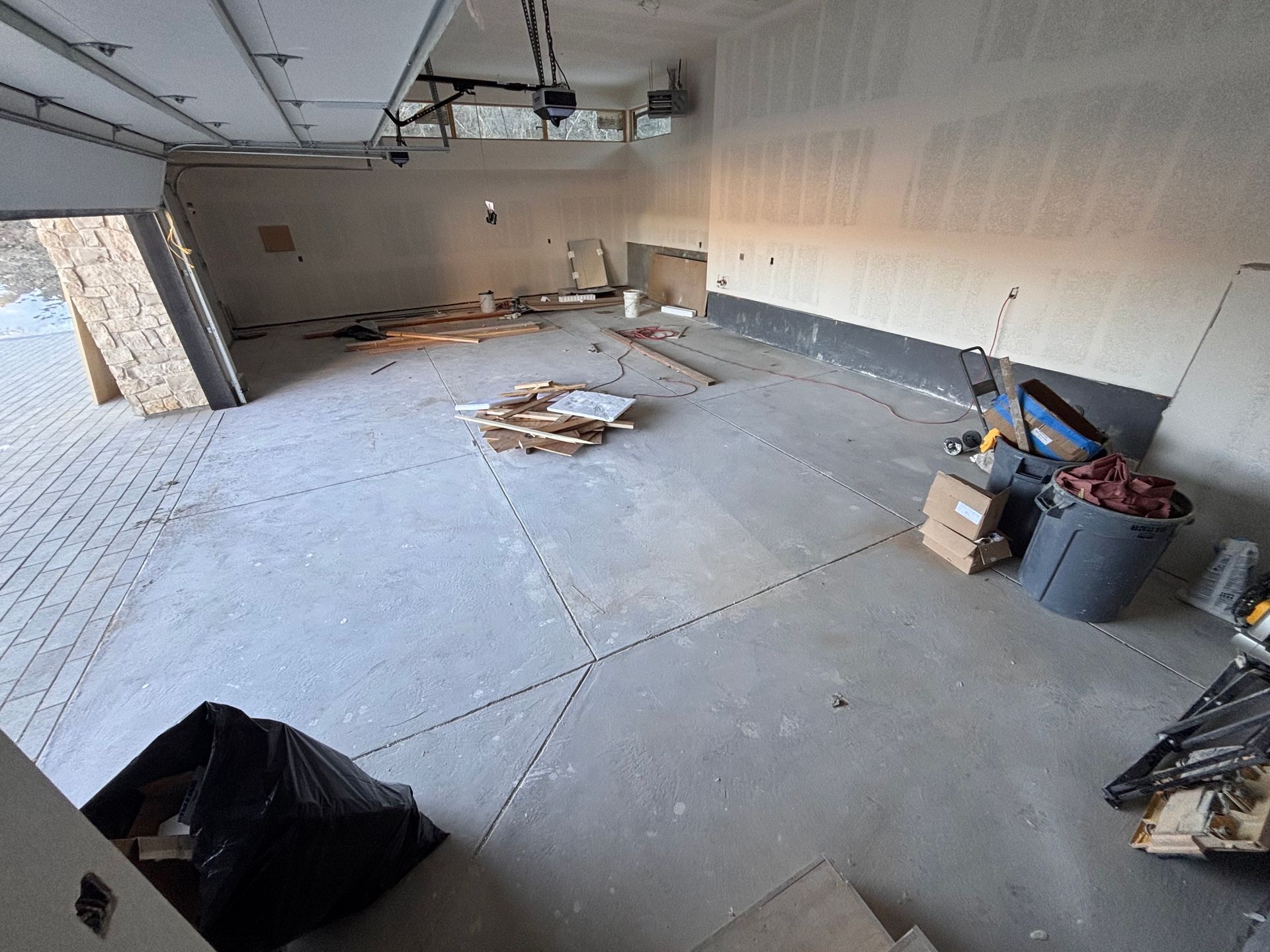 Interior of an unfinished garage with concrete floor and scattered construction materials.