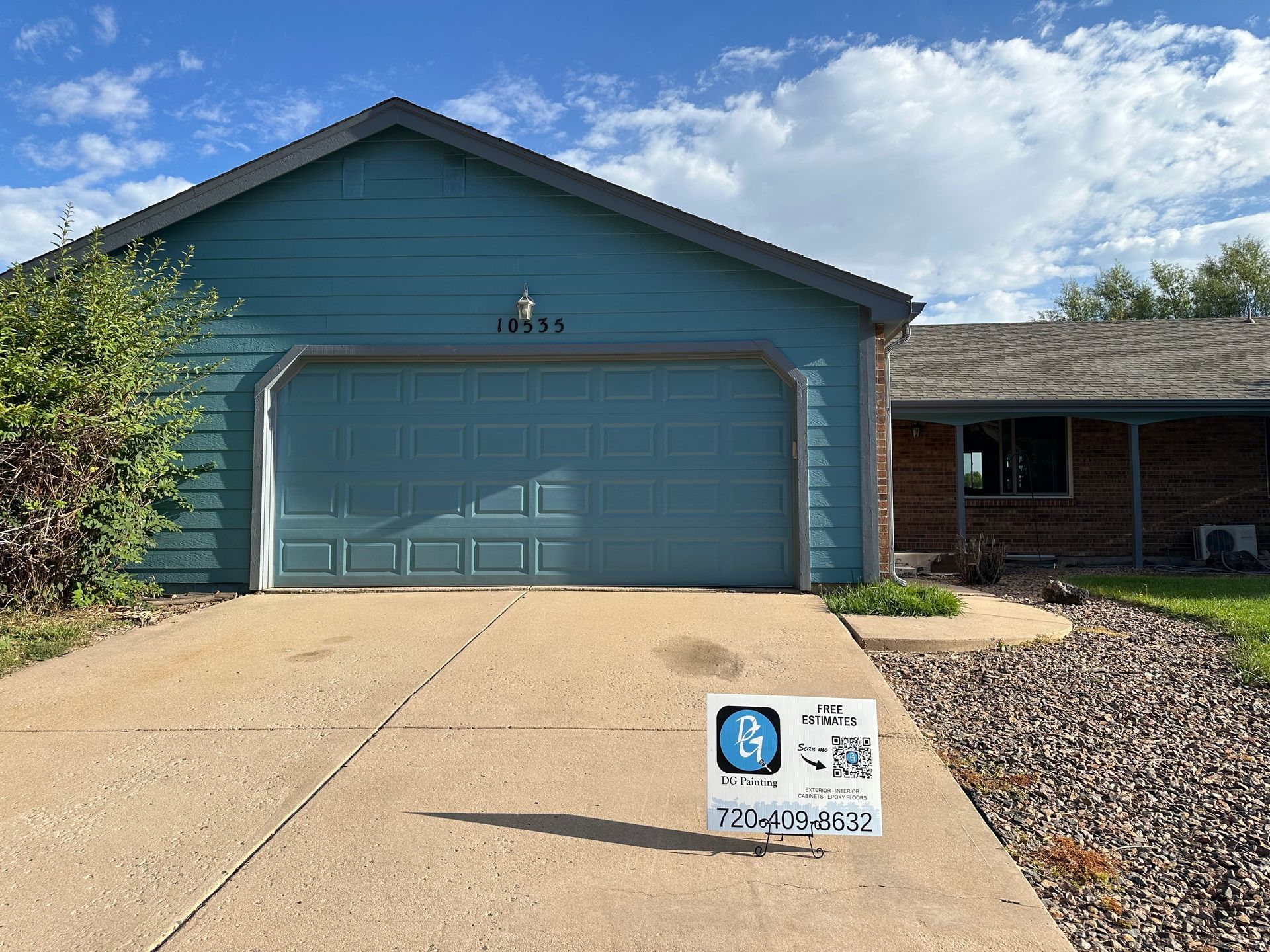 A house with a blue garage door and a for sale sign in front of it.