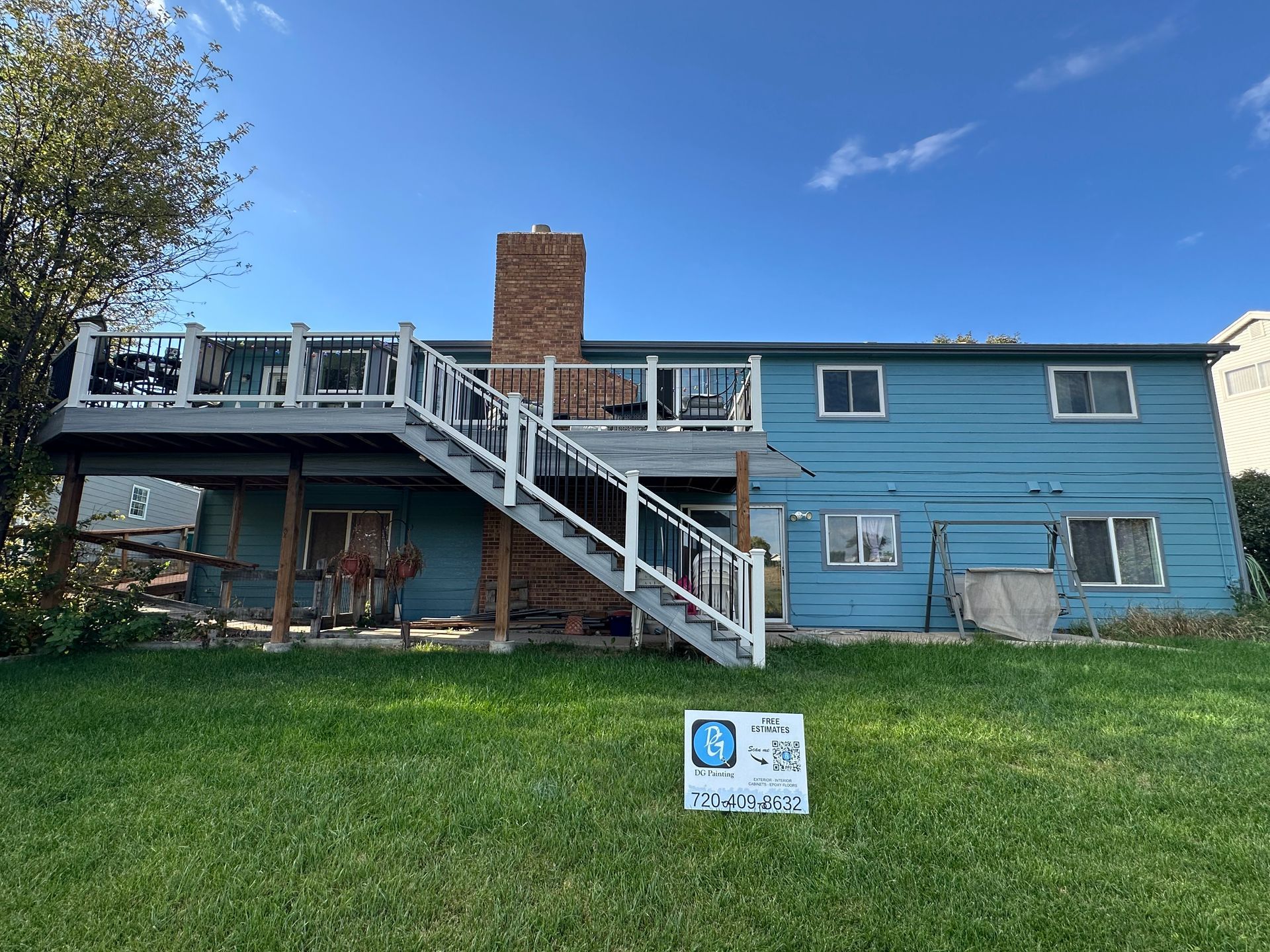 The back of a blue house with a large deck and stairs.