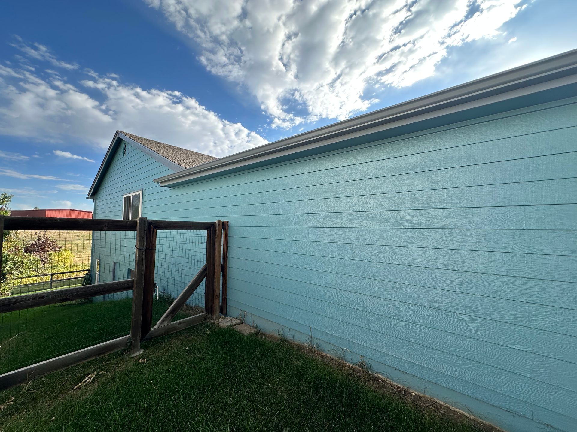 A blue house with a wooden fence in front of it.