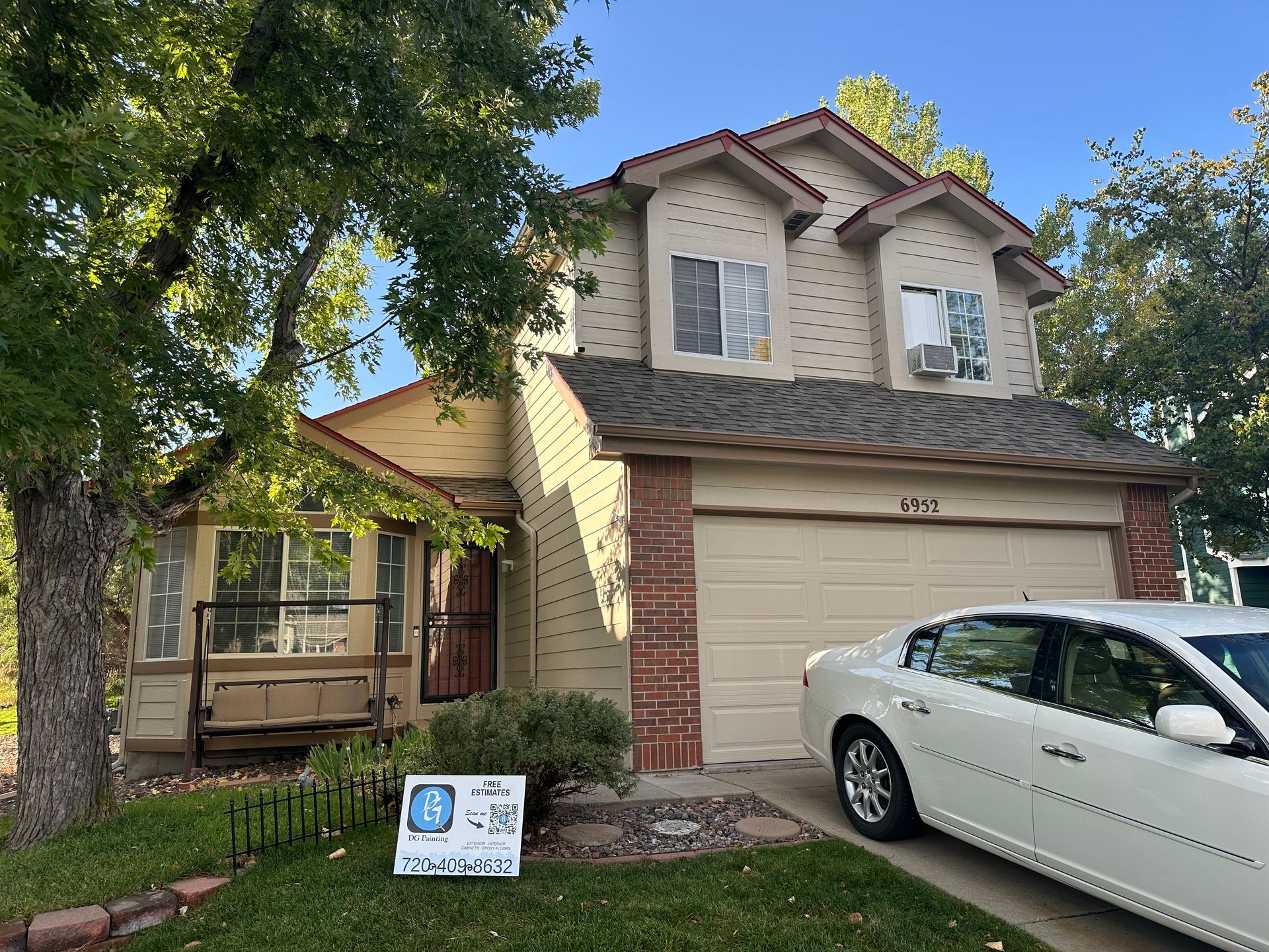 A white car is parked in front of a house.