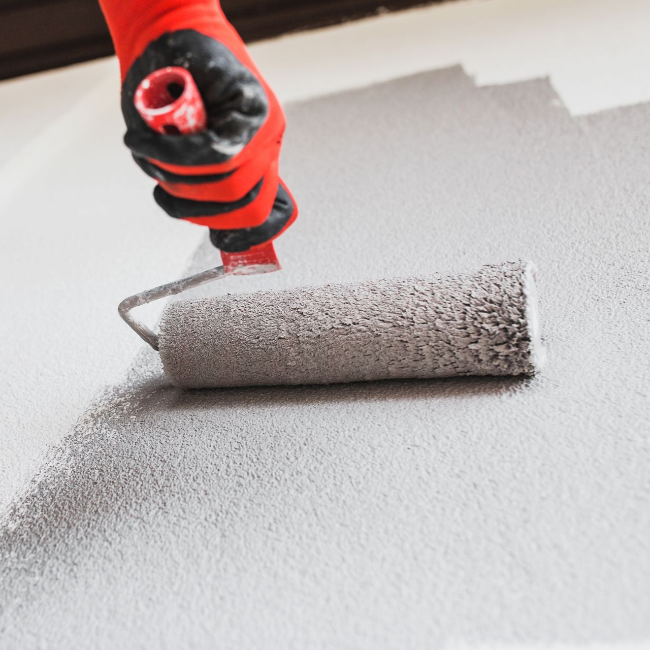 A person is painting a wall with a paint roller.