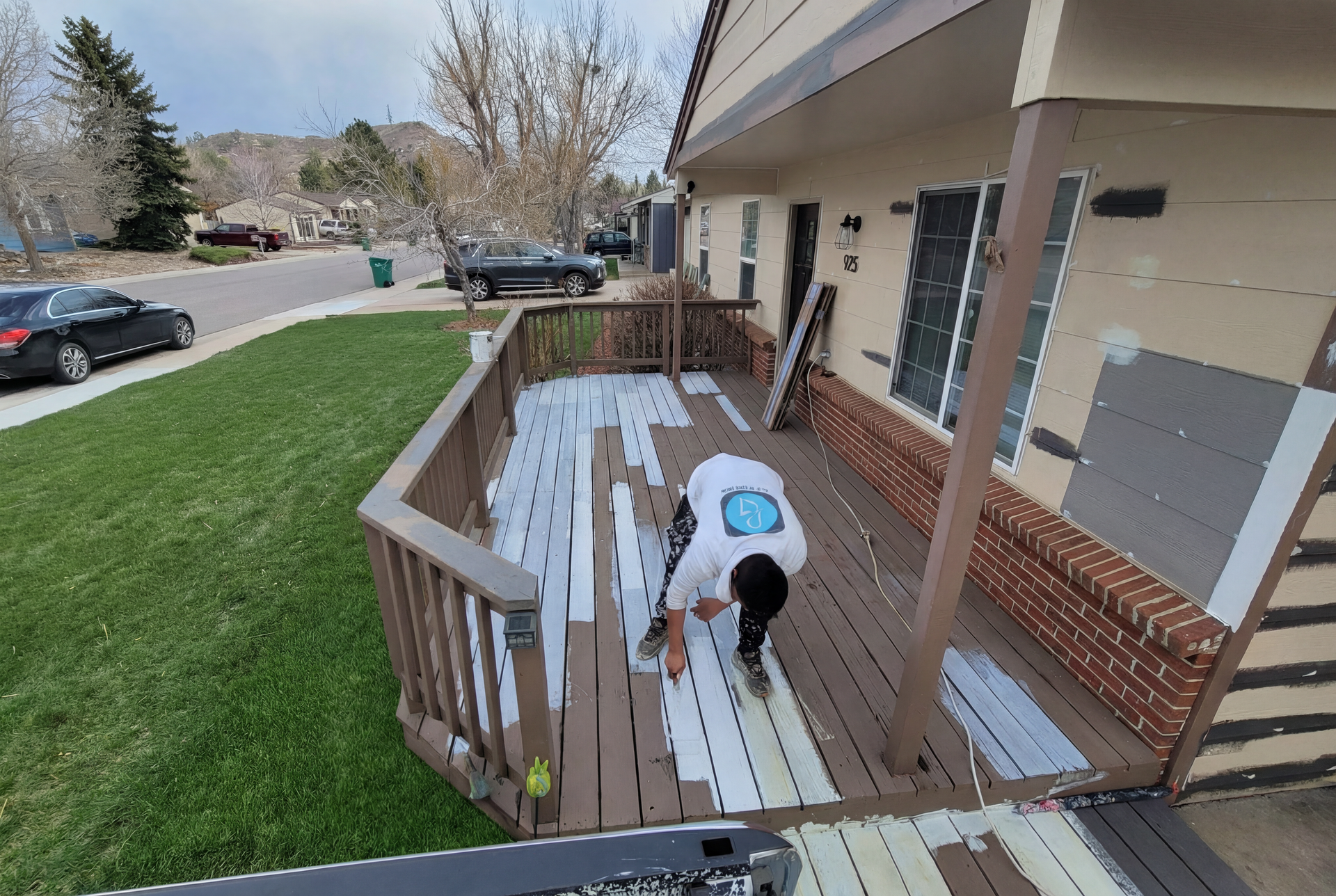 A man is painting a deck in front of a house.