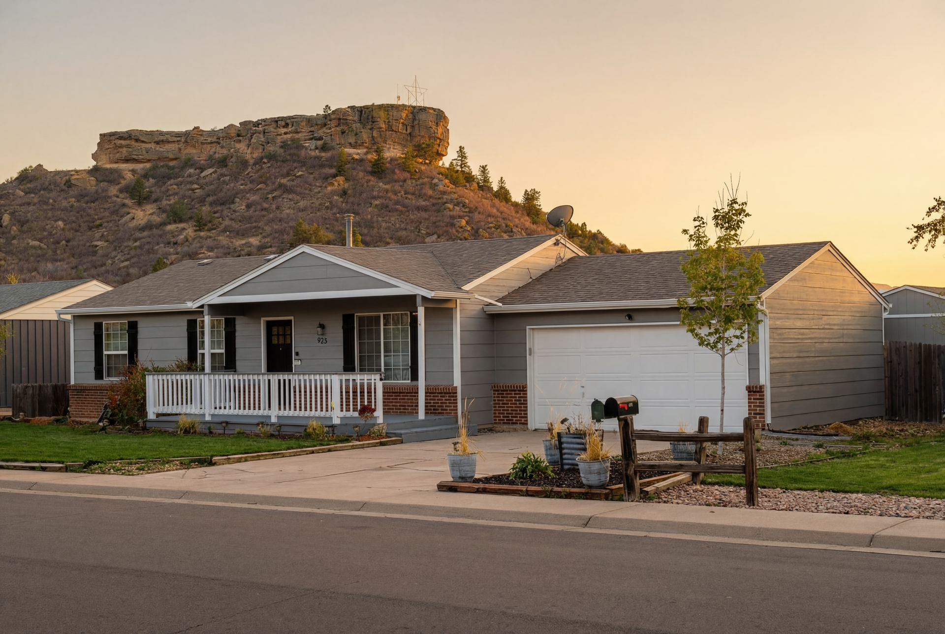 A house with a mountain in the background is sitting on the side of the road.