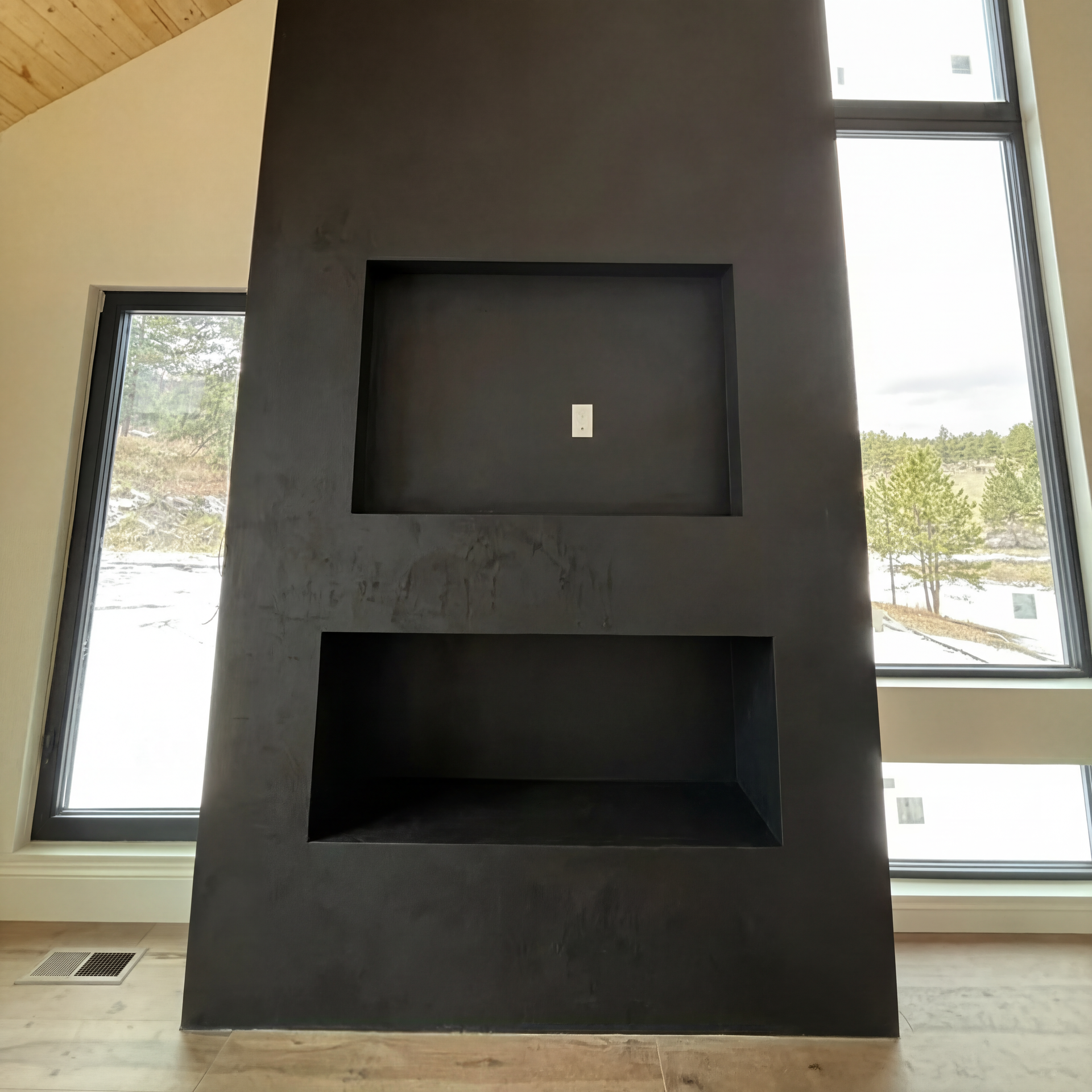 A fireplace is being built in a room with a large window