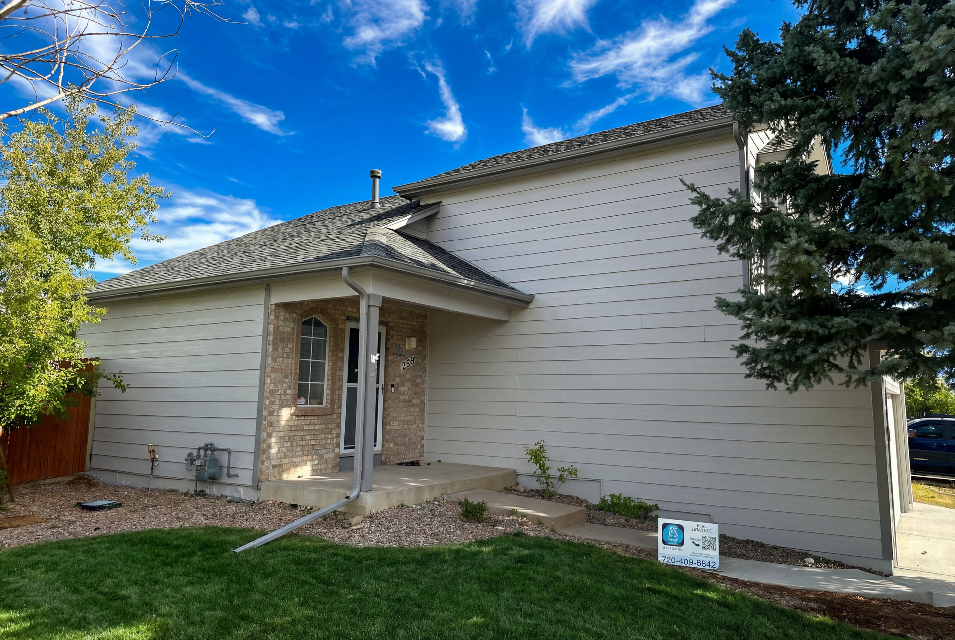 A white house with a porch and a sign in front of it.