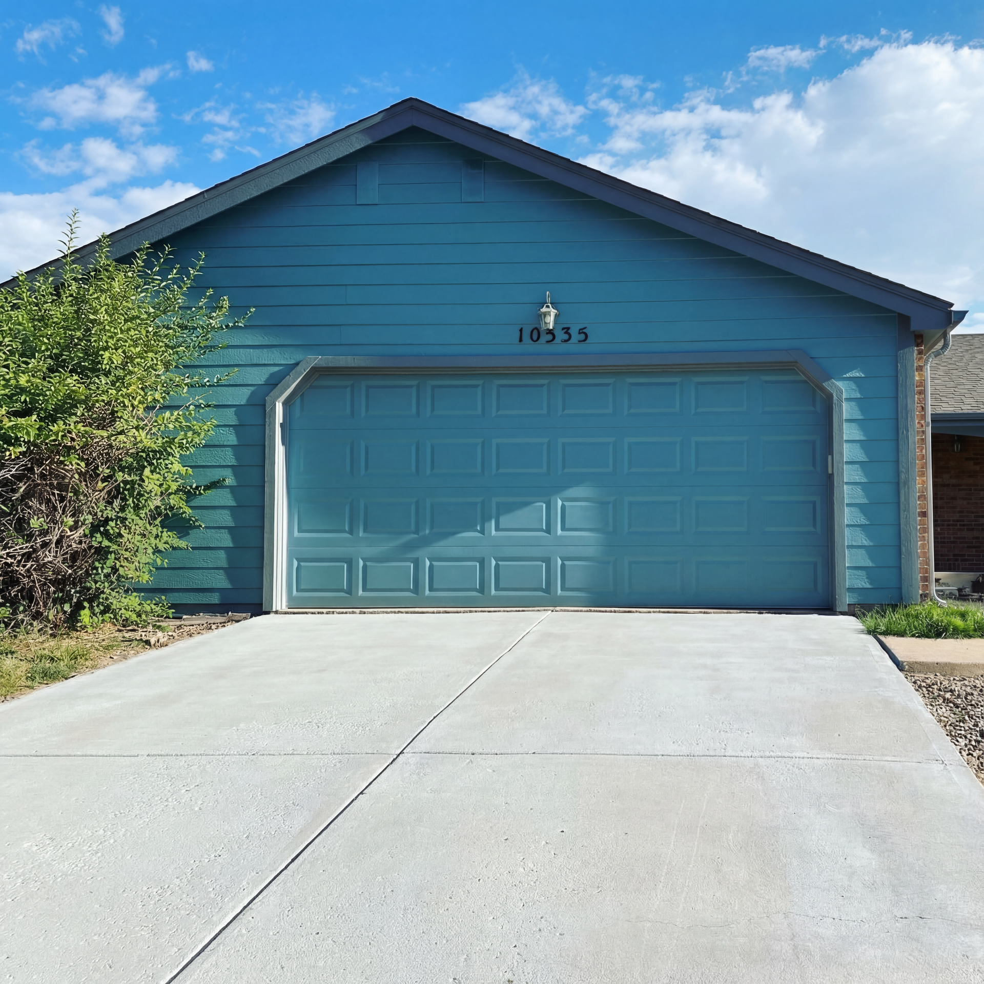 A house with a blue garage door and a for sale sign in front of it.