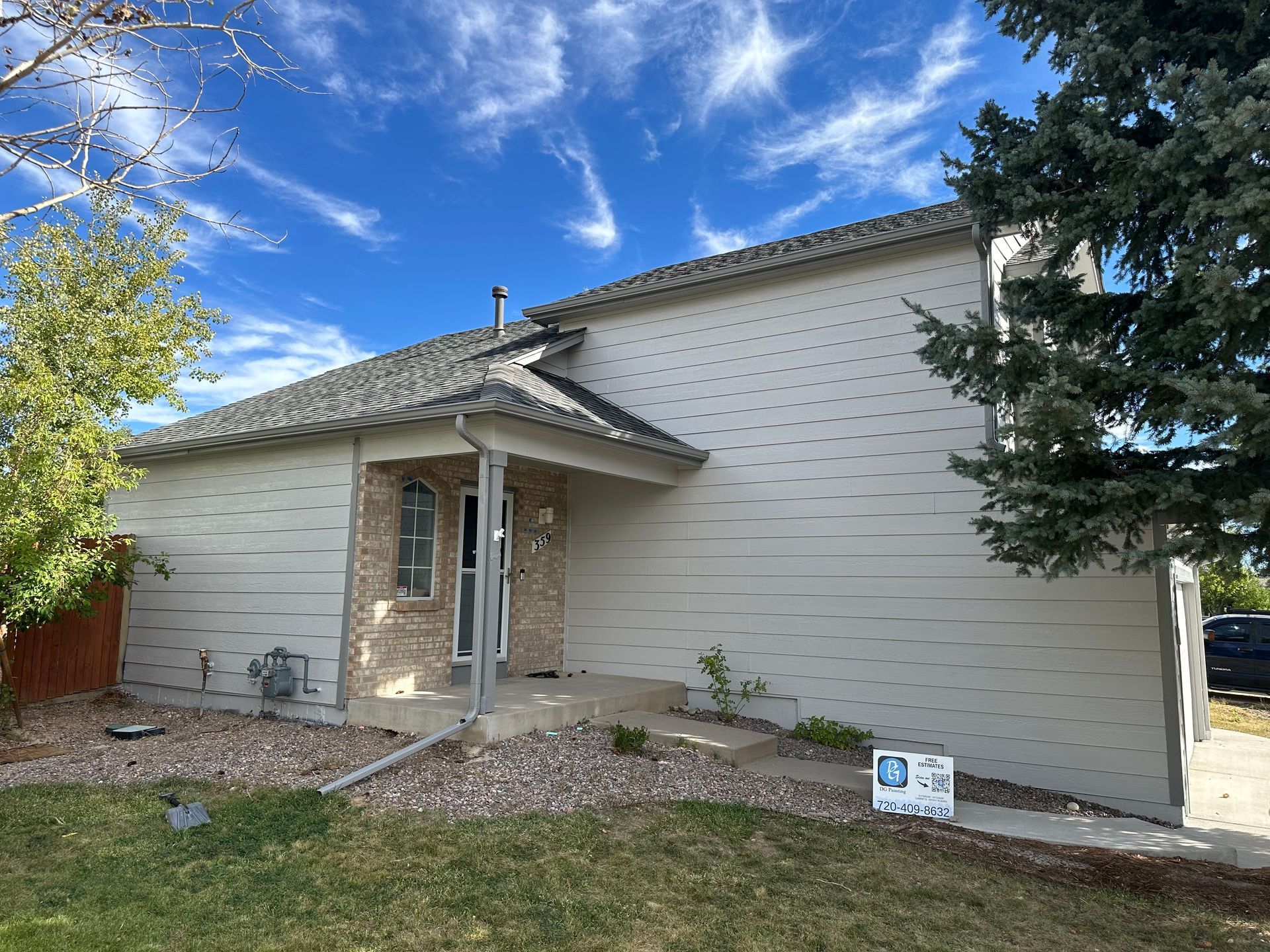 A white house with a porch and a sign in front of it.