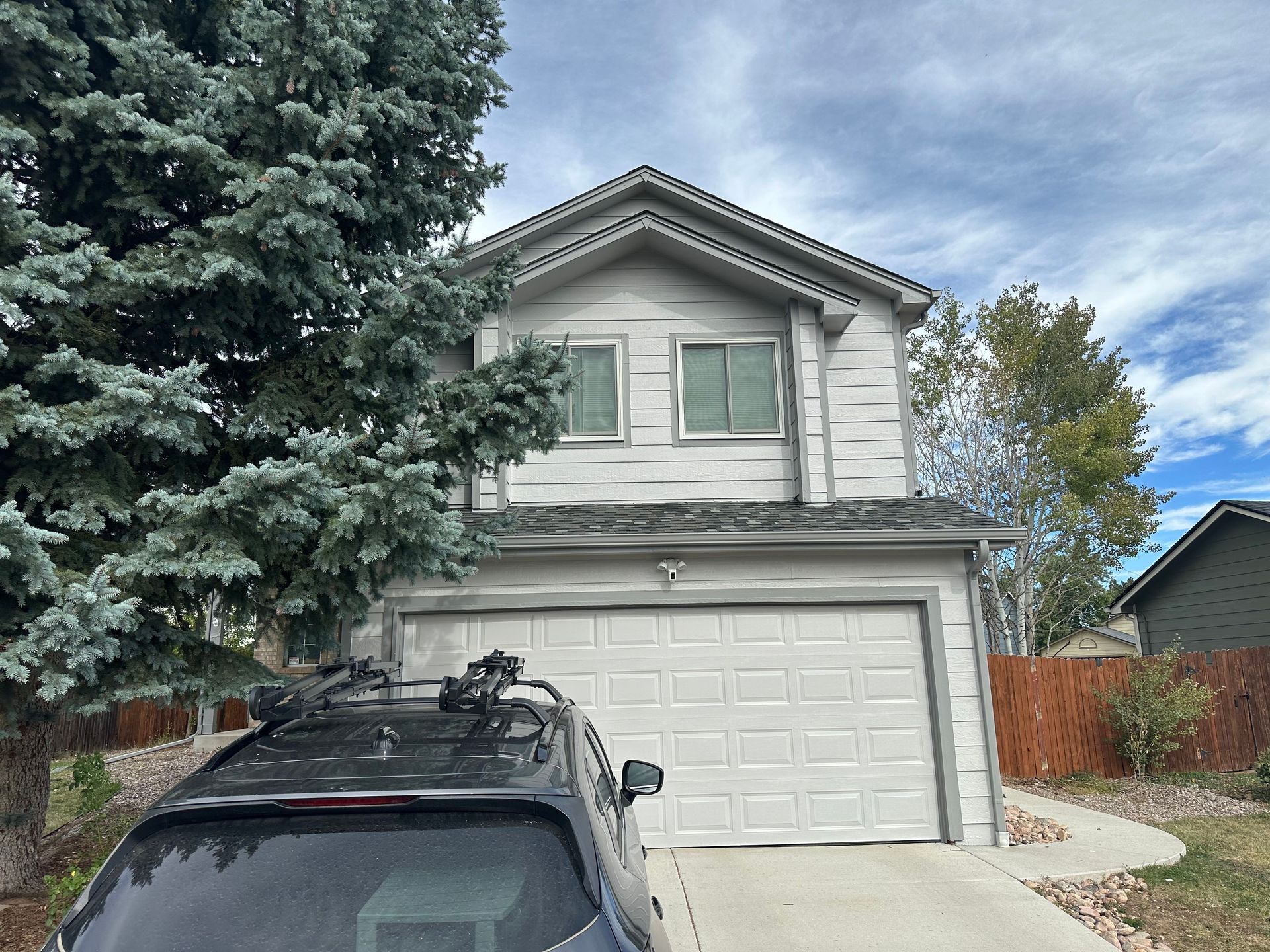 A car with a roof rack is parked in front of a house.