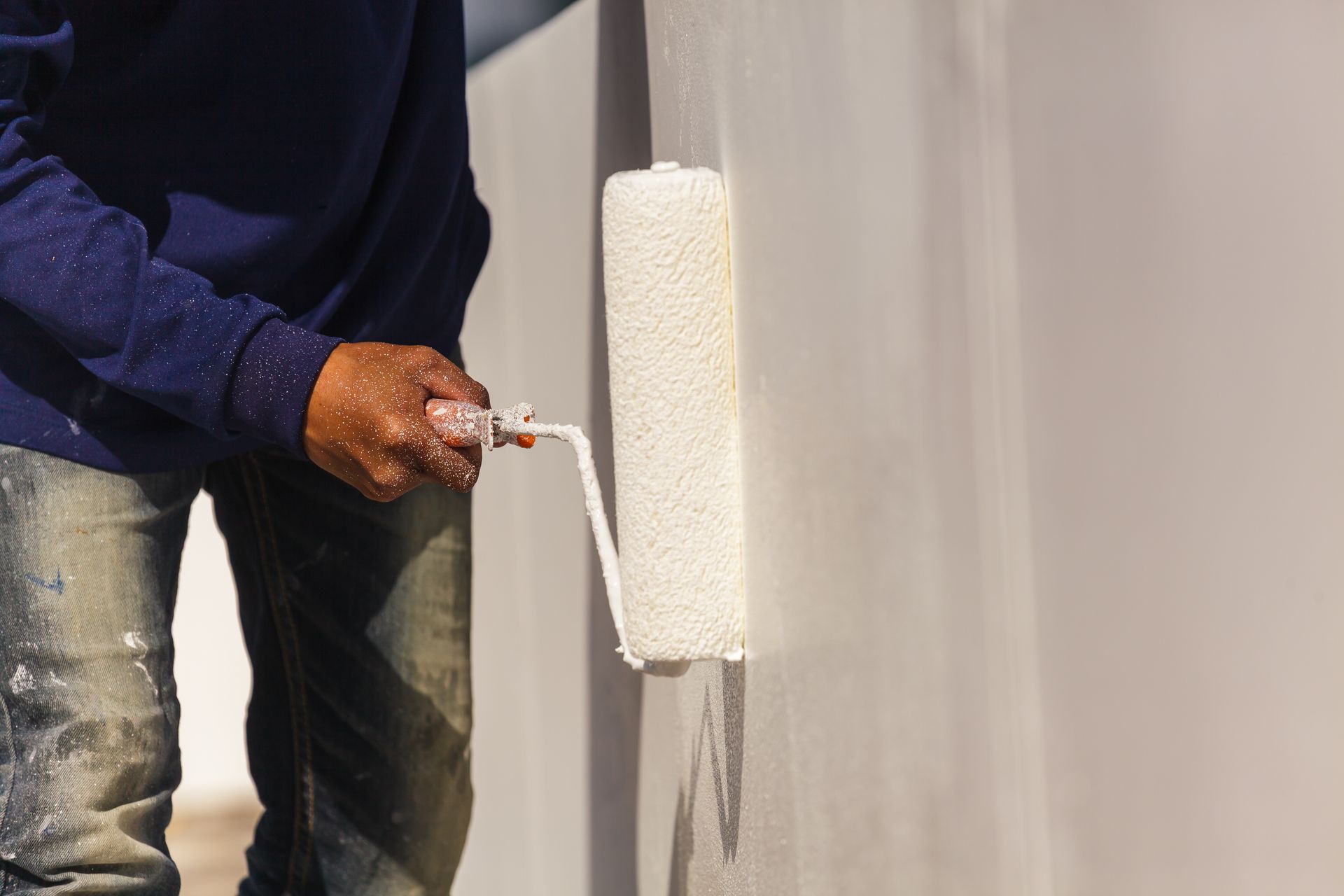 A man is painting a wall with a paint roller.