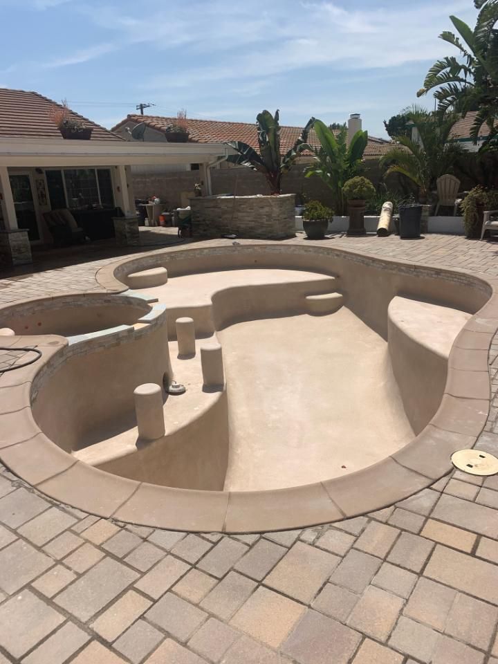 A large swimming pool is sitting on top of a brick patio.