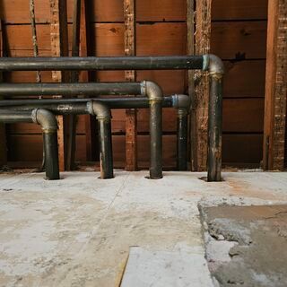 A bunch of pipes are lined up against a wooden wall
