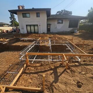 A house is being built in a backyard with a lot of dirt and concrete.