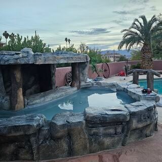 A swimming pool surrounded by rocks and palm trees