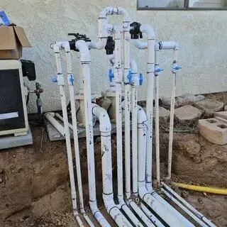 A bunch of white pipes are sitting in the dirt in front of a building.