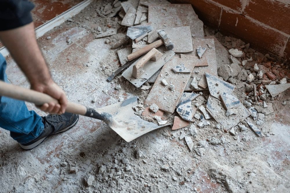 Person Shoveling Debris From a Demolished Floor, Including Broken Tiles and Cement. Construction Site Indoors — Campbell Built in Nelson Bay, NSW
