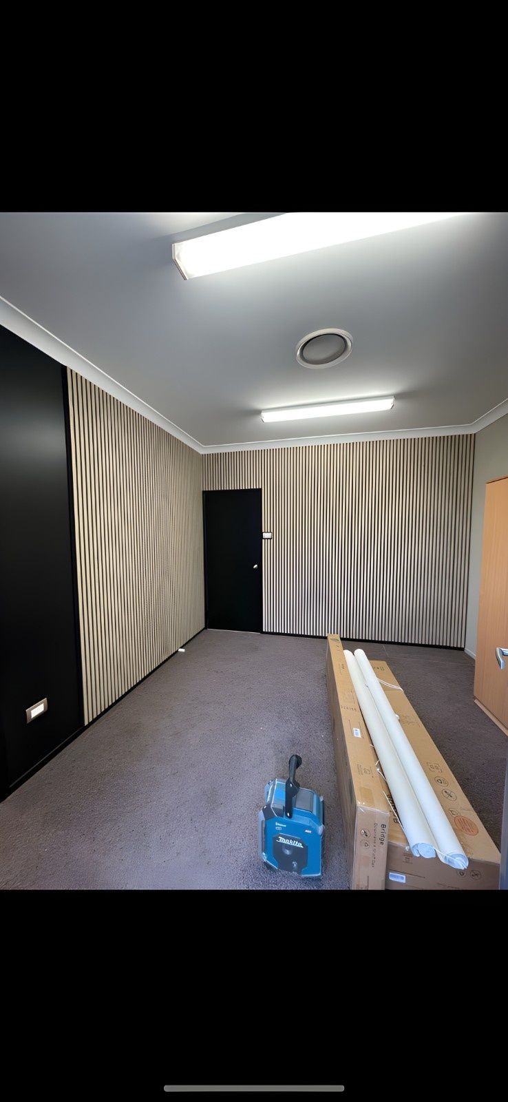 Interior Room With Patterned Wallpaper, a Black Door, and Tools on the Floor. Fluorescent Lights and Ceiling Details Are Visible — Campbell Built in Nelson Bay, NSW