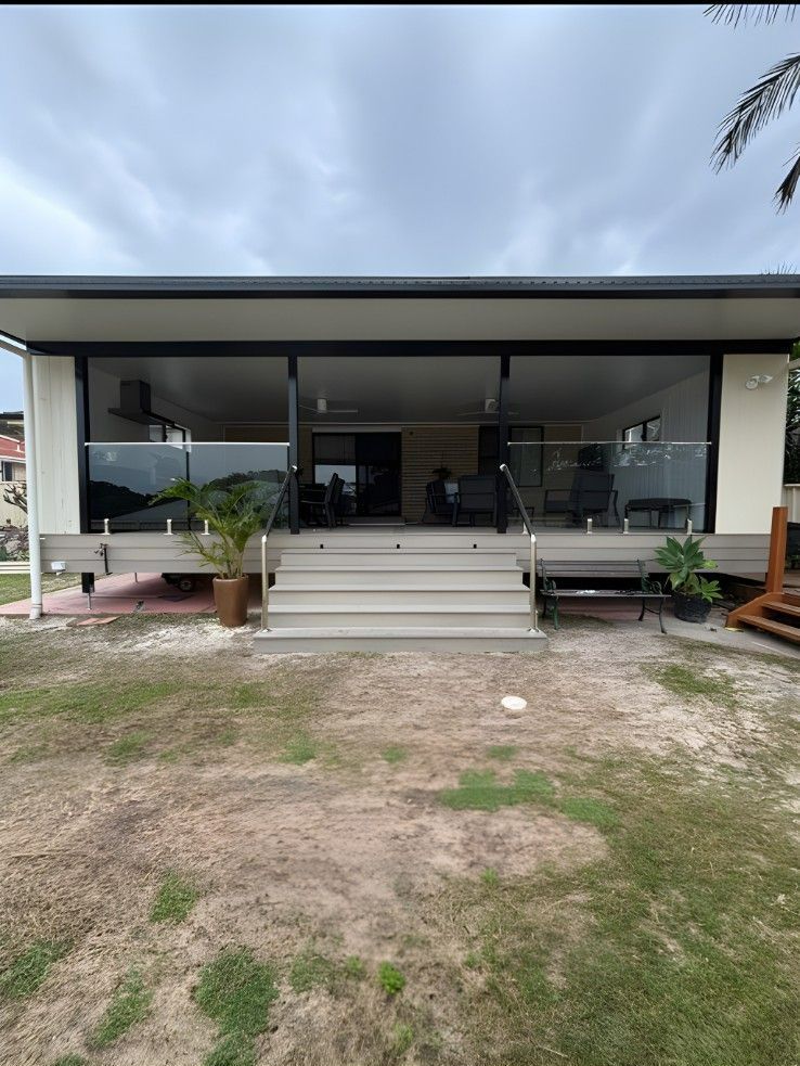 A Modern House With Large Glass Windows and a Gray Roof. a Set of Steps Leads to the Entrance, and a Lawn is in Front — Campbell Built in Nelson Bay, NSW