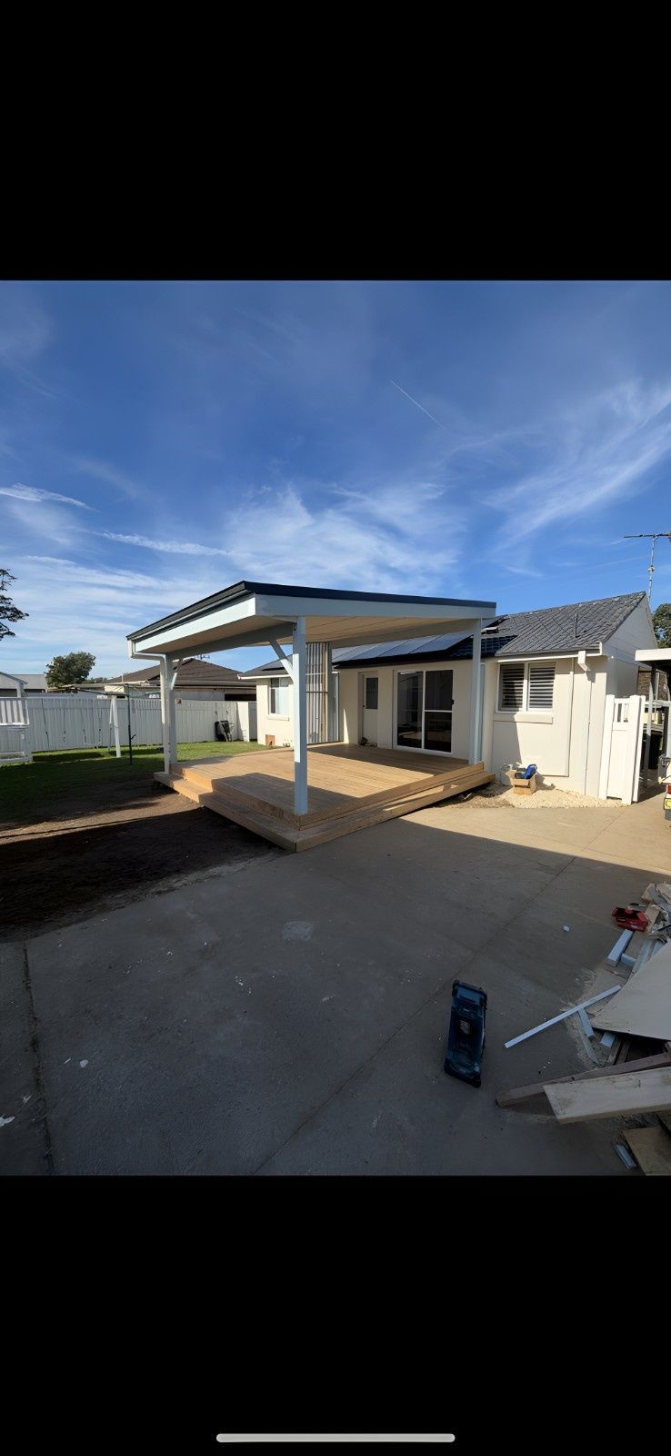 A White Carport Covers a Wooden Deck, With a House in the Background. the Sky is Blue With Some Clouds — Campbell Built in Nelson Bay, NSW
