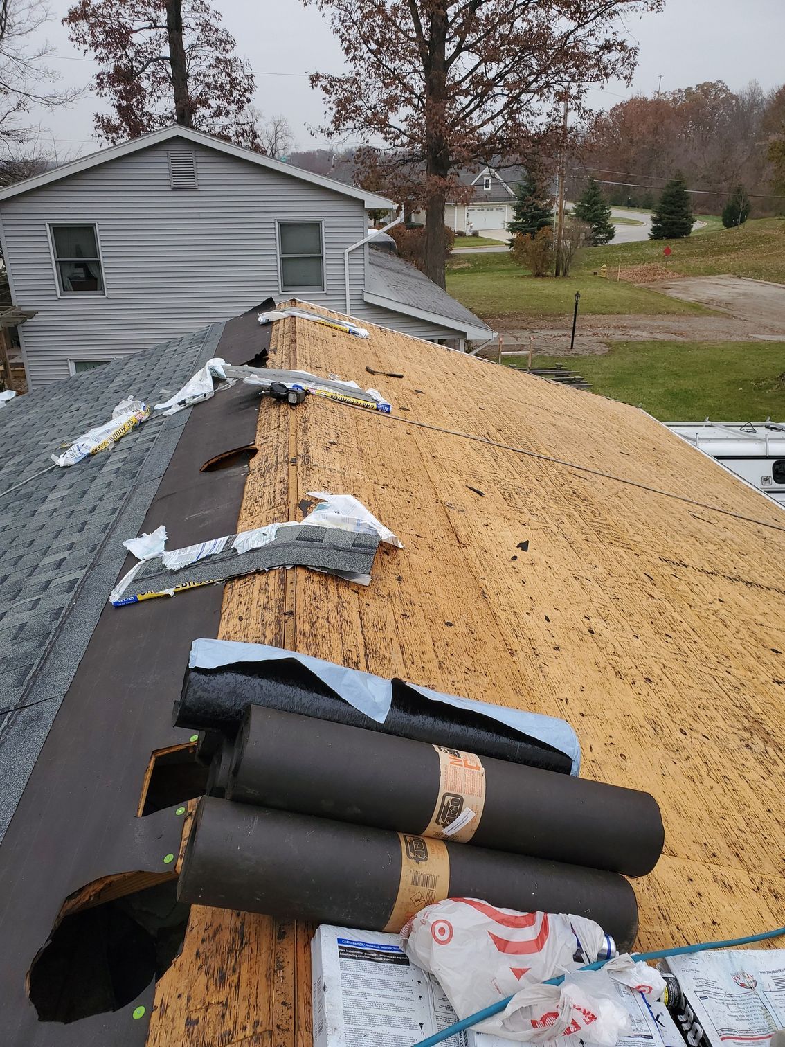 Roof partially covered with old and new materials during a renovation, overcast day.
