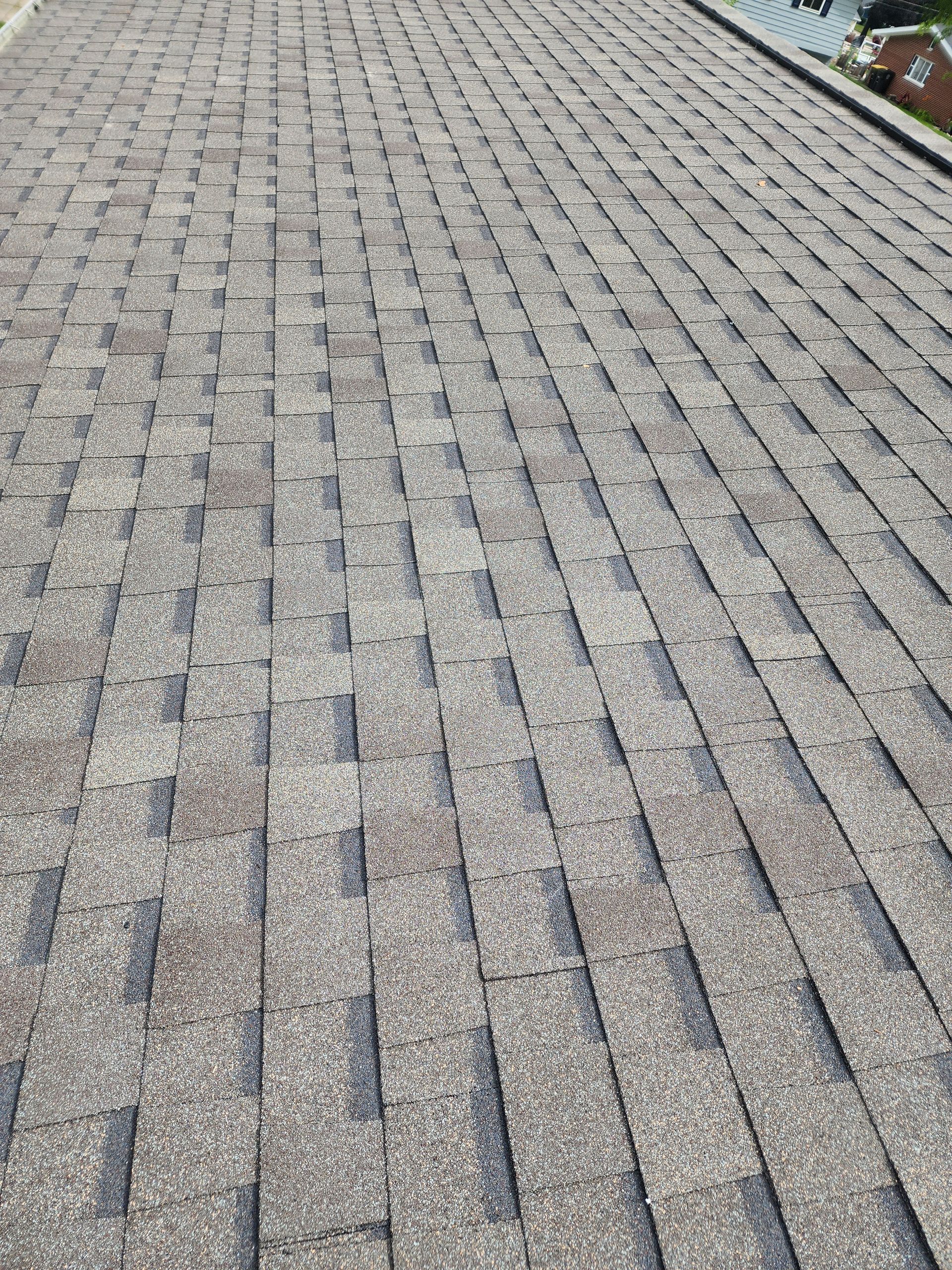 Gray asphalt shingle roof, angled view, covering a residential home.
