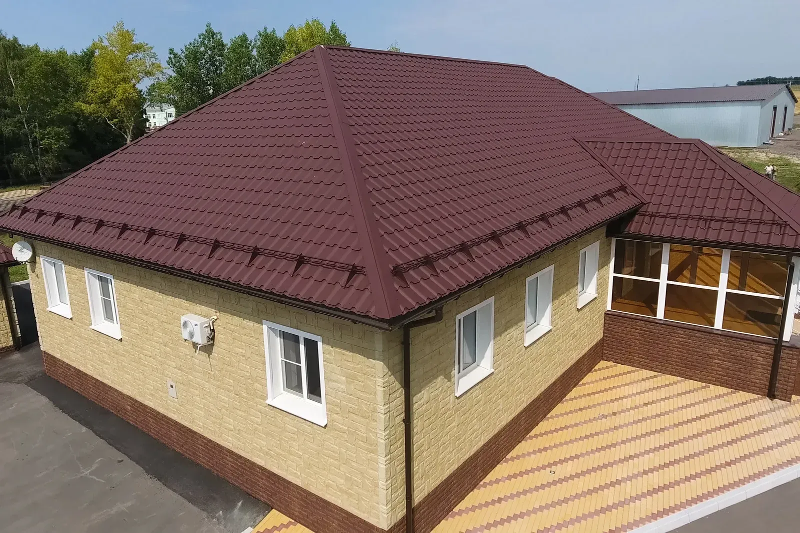 Brown brick building with brown roof and white windows; outdoors.