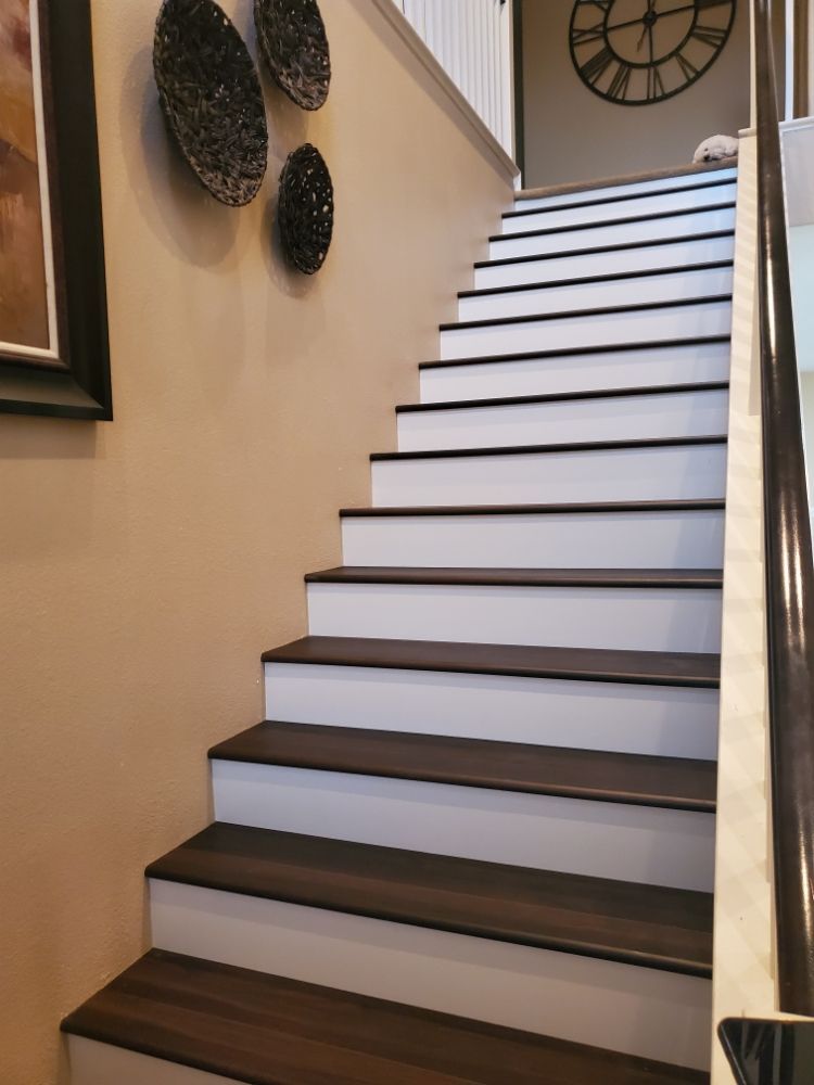 A staircase with dark wood treads and white risers, leading up to a wall featuring three dark decorative wall discs.