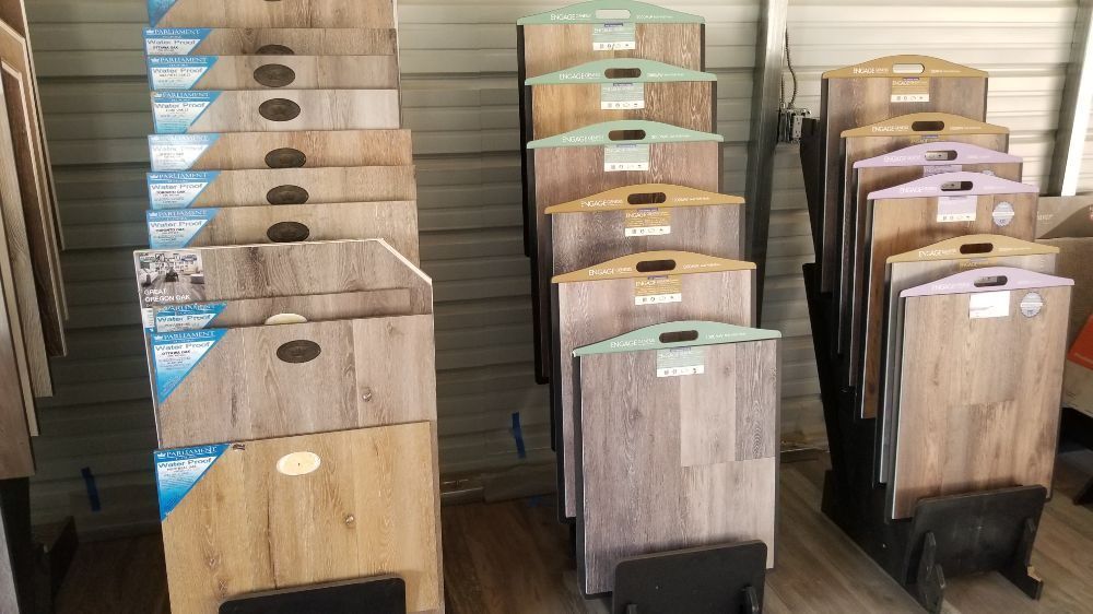 Samples of light-toned wood-look laminate flooring panels displayed on racks in a showroom.