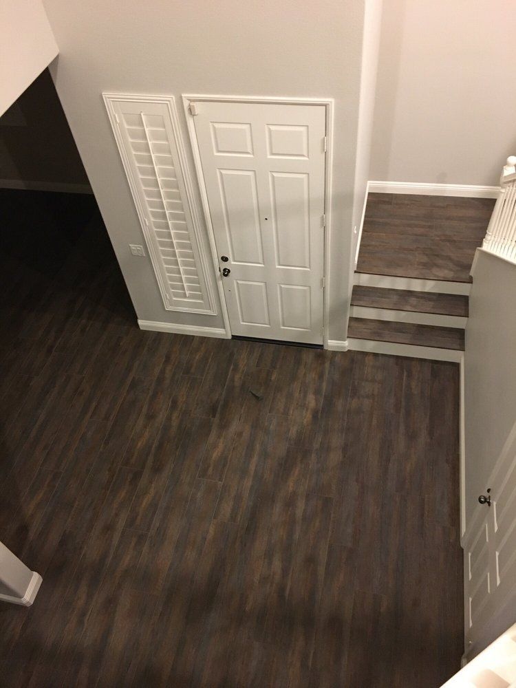 An elevated view of a foyer with dark wood floors, a white front door with a side window, and a short set of stairs.