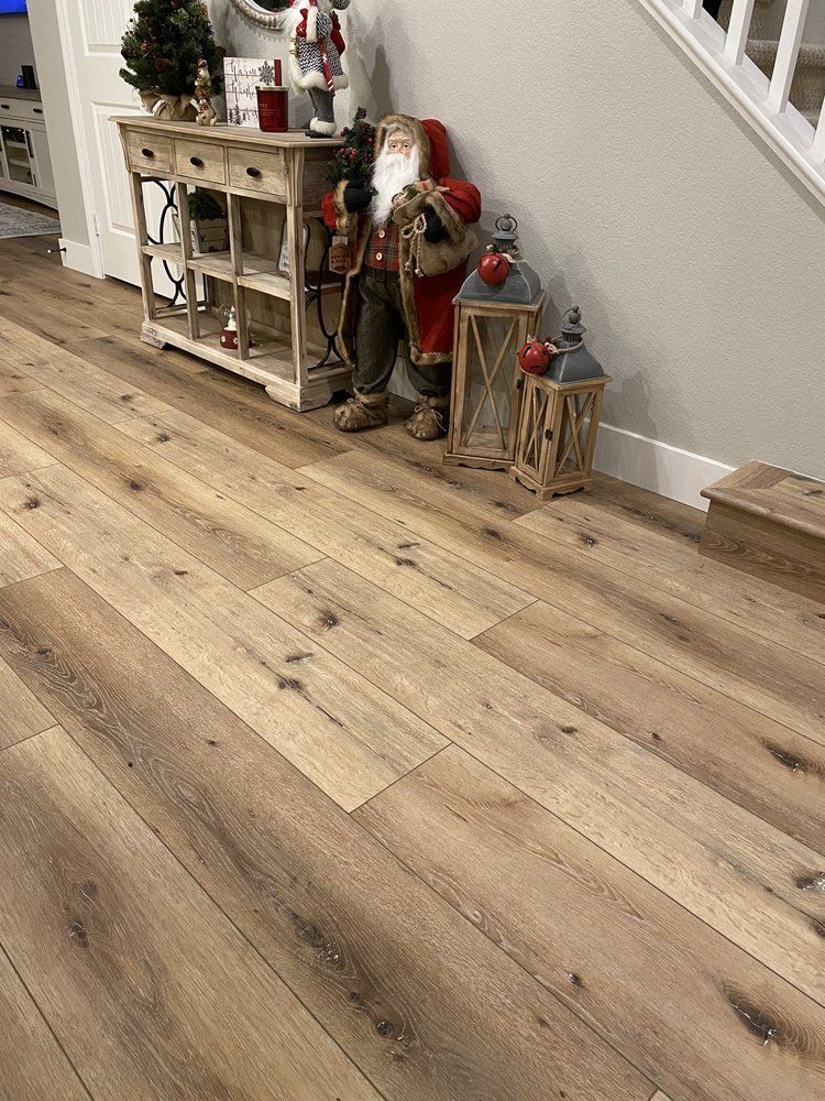 A festive entryway features wood-look flooring, a weathered wooden console table, a Santa figure, and two lantern decors.