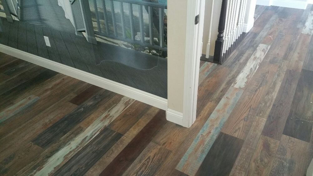 Multi-tonal wood flooring with planks of varying shades of brown, gray, and tan installed in a home hallway.