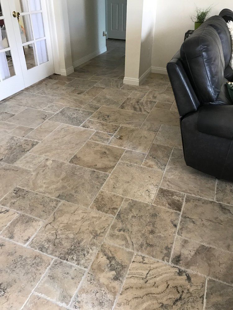 Light brown, textured travertine stone flooring in a rectangular pattern, viewed from a high angle inside a home.