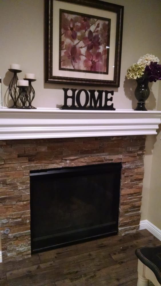 A stone fireplace with a white mantel, decorated with candles, a 