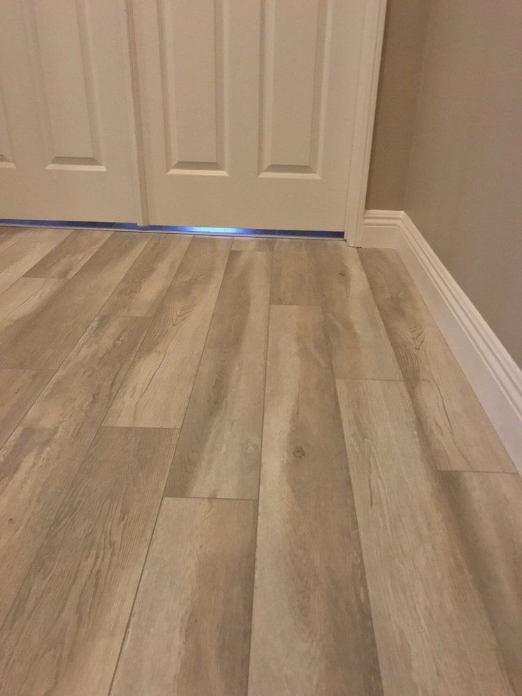 Light wood-look plank flooring meets white baseboards and a closet door.
