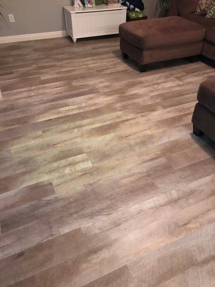 Light-colored wood-look flooring with a glowing yellow stain illuminated by a UV light in a living room.