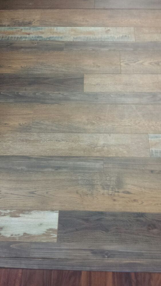 Multi-colored wood-look planks with varying tones of brown, gray, and cream, installed in a horizontal pattern.