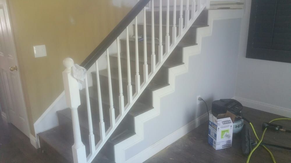 Interior stairs with white railings and risers, dark carpeted steps, and a tool box on the floor nearby.