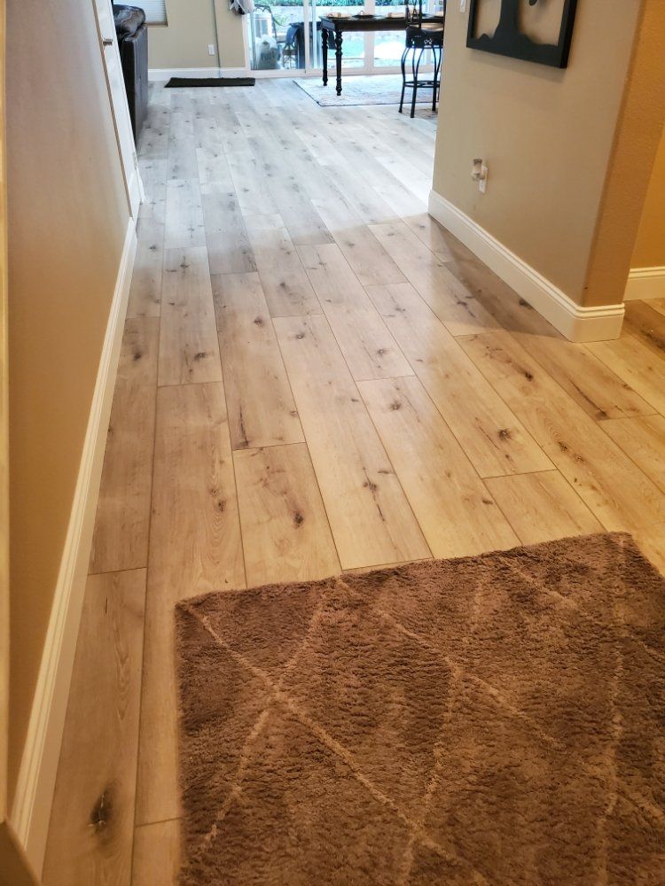 A hallway with light-colored, wood-look plank flooring.