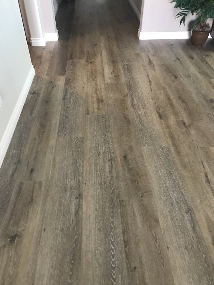 Wide-angle view of brown, wood-look vinyl plank flooring extending into a residential hallway.